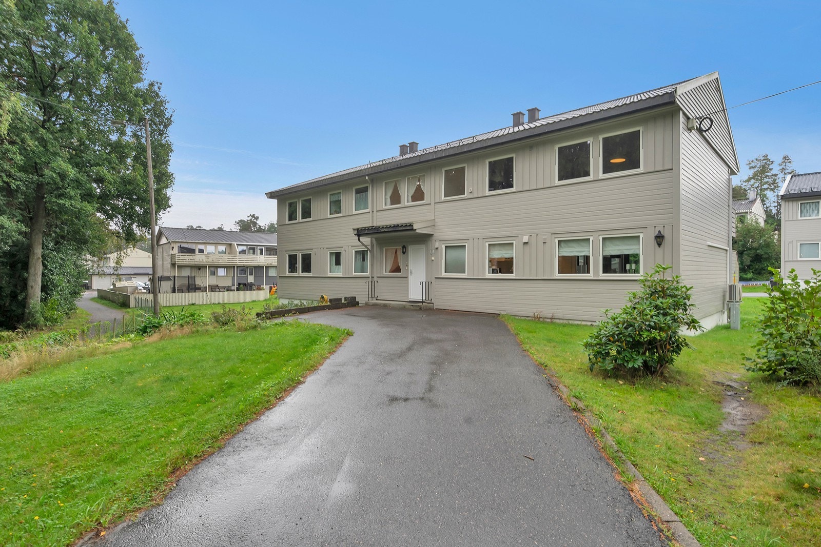 Asfaltert inngangsparti. Plen og beplanting gjør området koselig. Galleribilde
