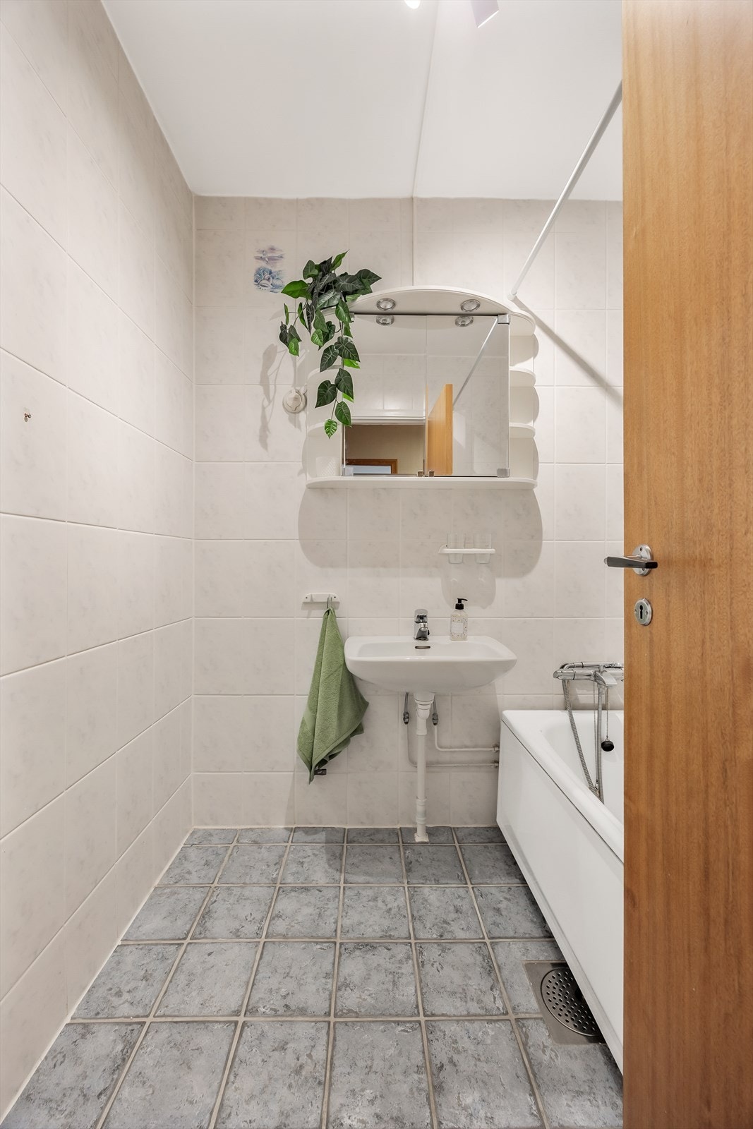 Flislagt bad med skap med speilfronter, servant og dusj i badekar. Galleribilde