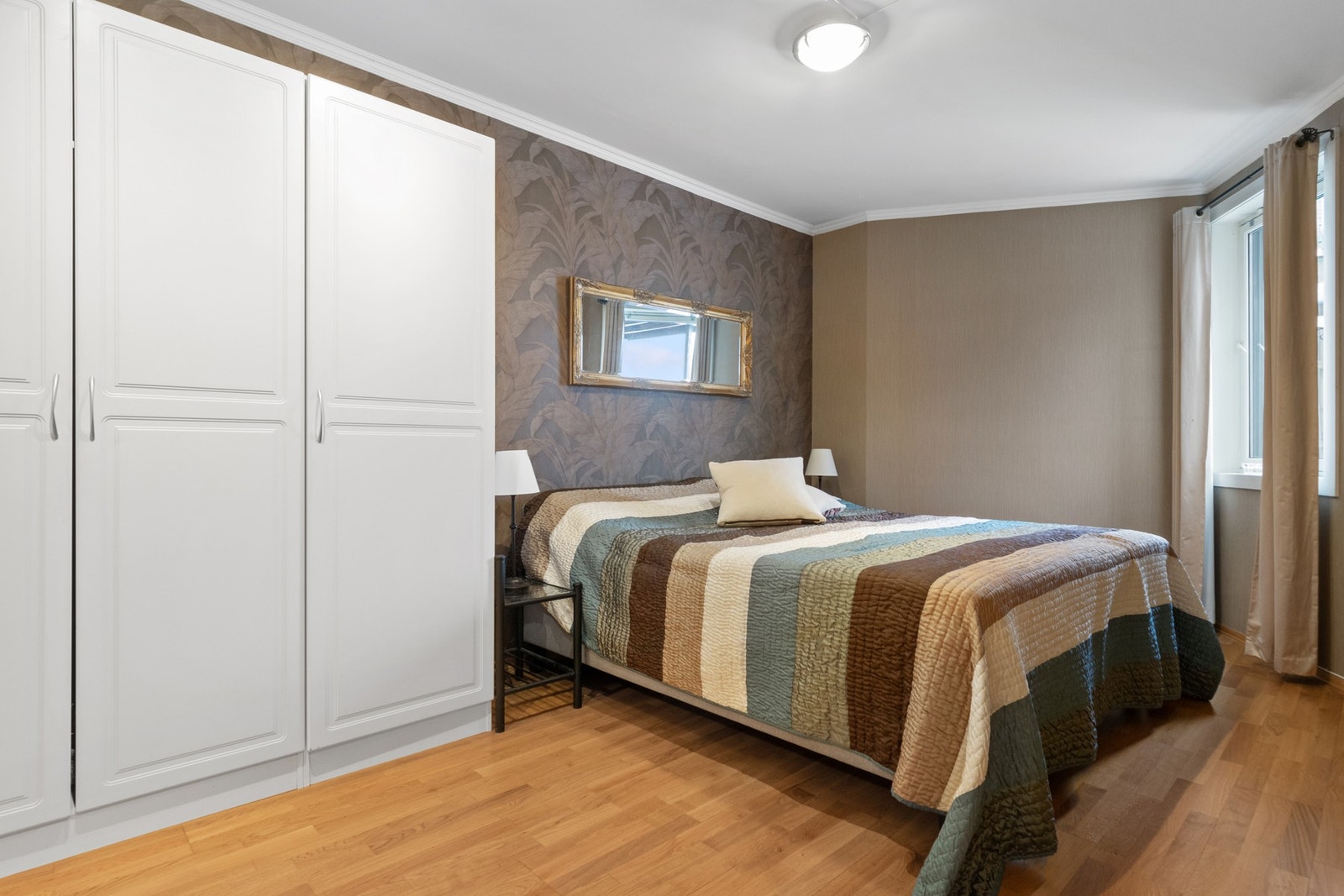 Boligens hovedsoverom har plass til en dobbeltseng med nattbord på hver side og skap/kommode til oppbevaring. Galleribilde