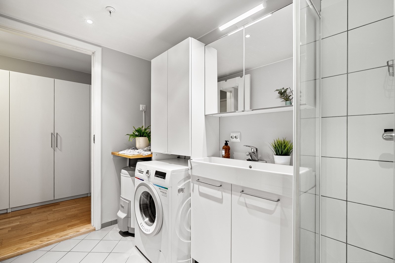 Badet har vegghengt toalett, dusjhjørne, baderomsmøbel og opplegg til vaskemaskin. Galleribilde