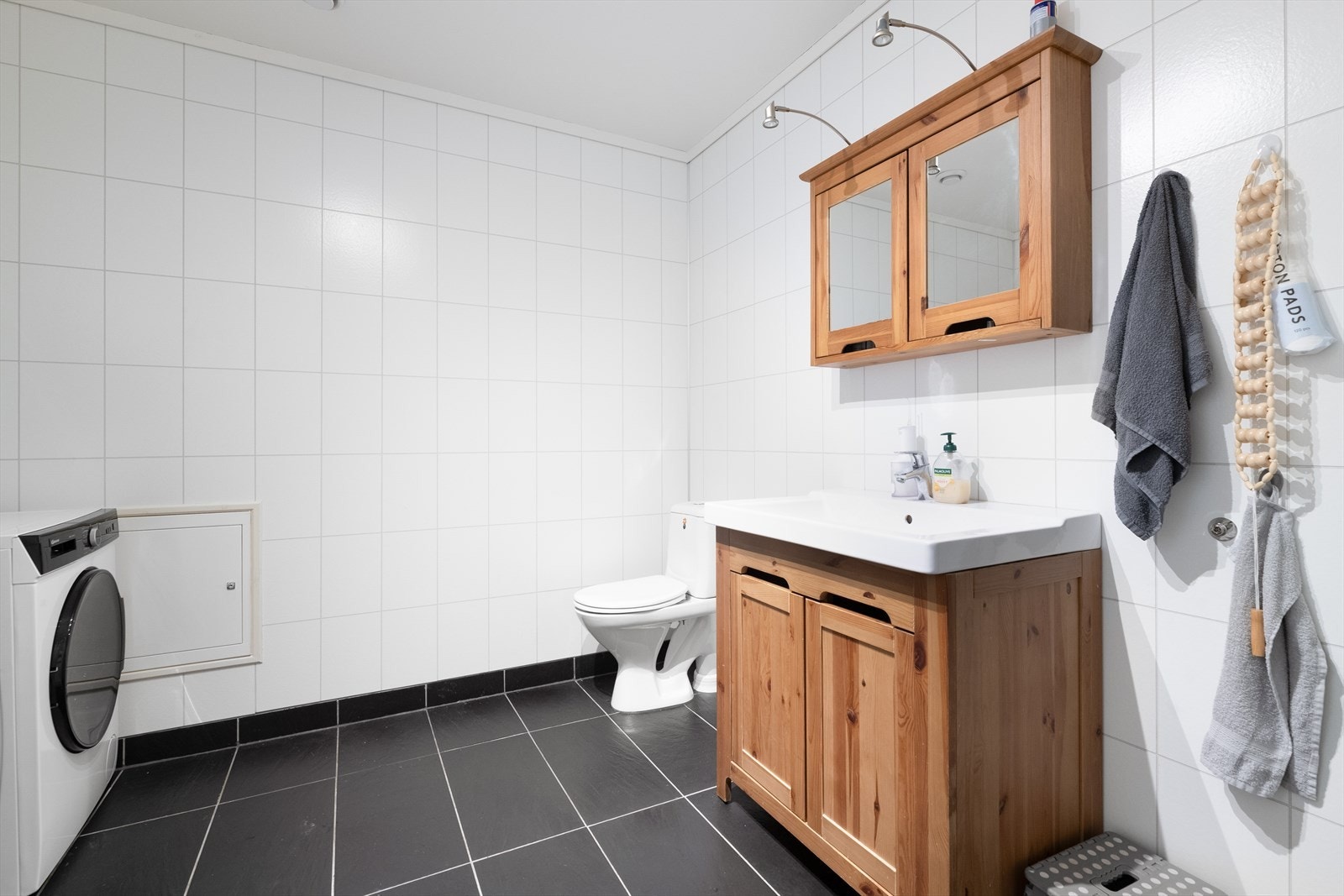 Badet er innredet med servantmøbel, toalett, dusjkabinett og opplegg for vaskemaskin. Galleribilde