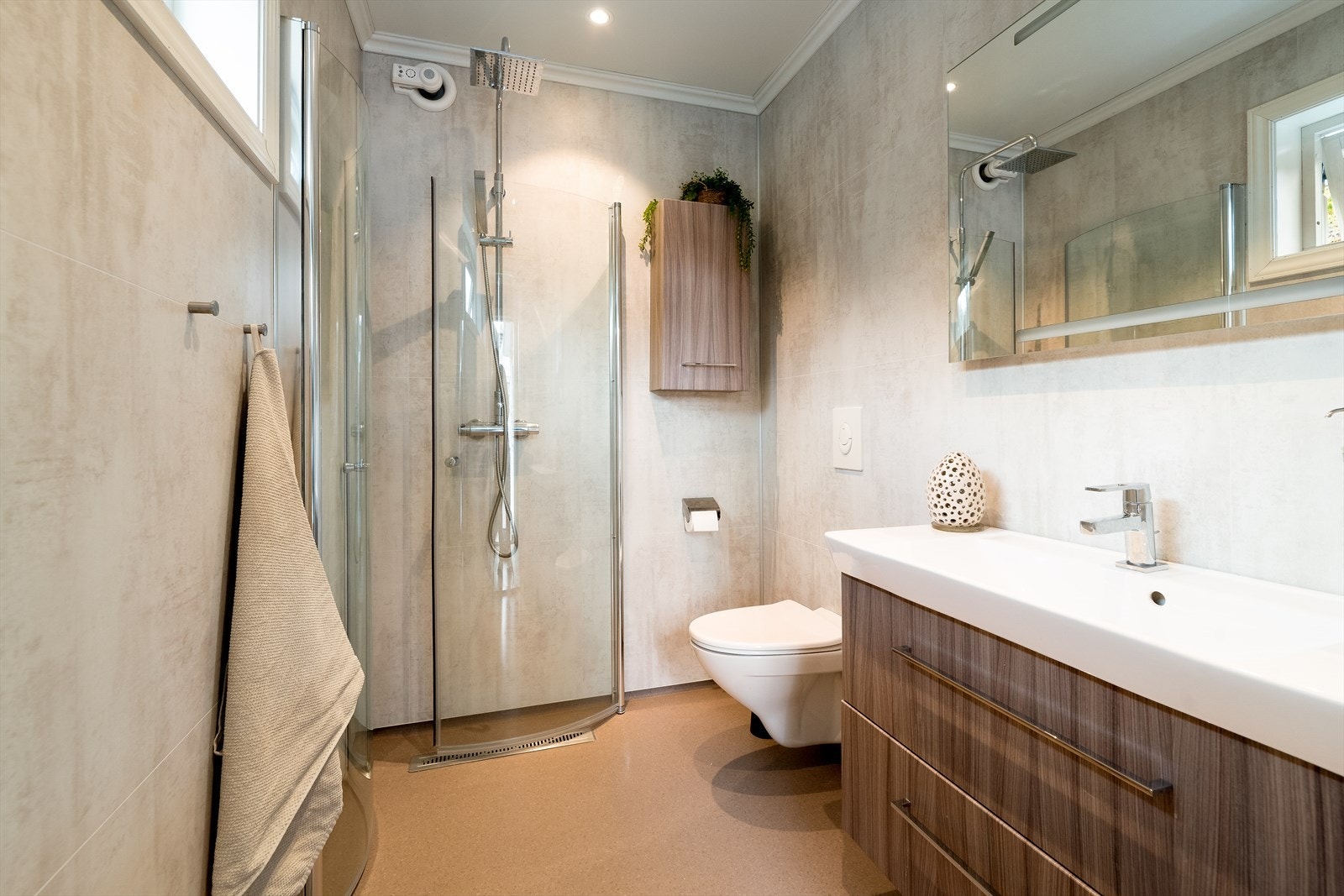 Det andre badet ligger ved inngangspartiet og innehar veggmontert toalett, dusjvegger/hjørne og servantinnredning med skuffer og speil med lys. Galleribilde