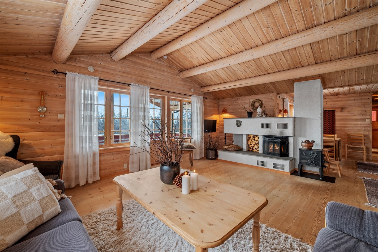 Stuen har en lun atmosfære med tregulv, trepanel og store rundåser. Galleribilde