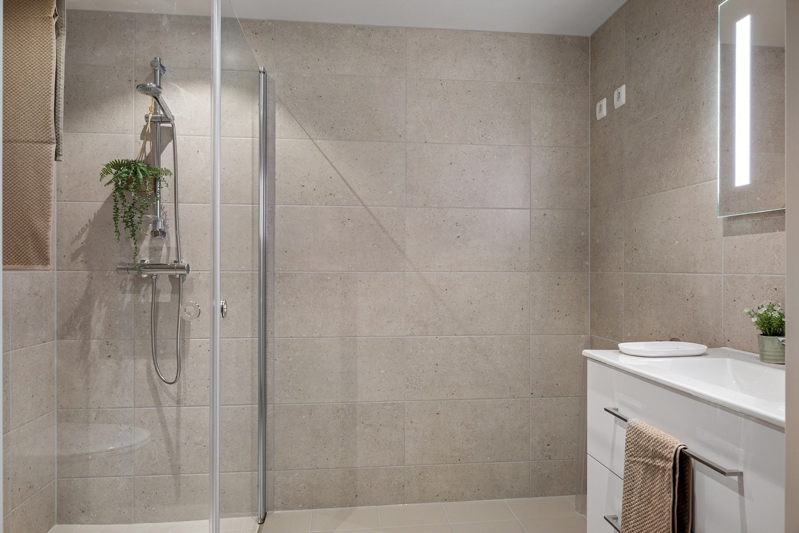 Romslig og helfliset bad med dusjsone og moderne baderomsinnredning. Galleribilde