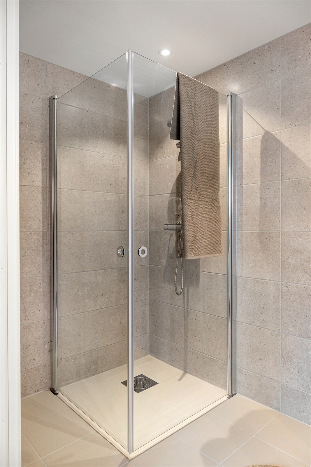 Stilren dusjsone med glassvegger og gjennomført flisvalg. Galleribilde