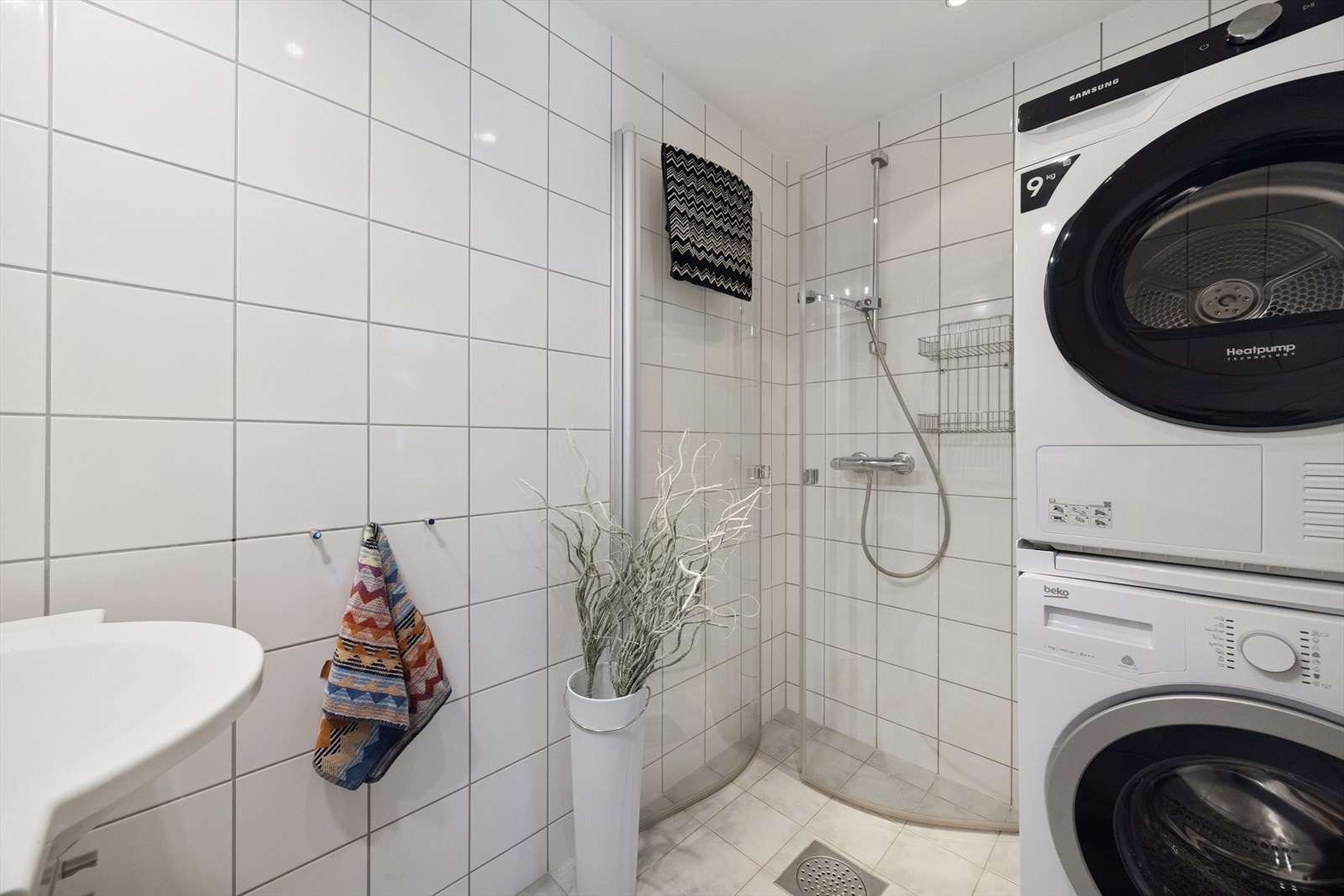 Badet er flislagt og utstyrt med dusjhjørne med glassvegger og opplegg for vaskemaskin. Galleribilde