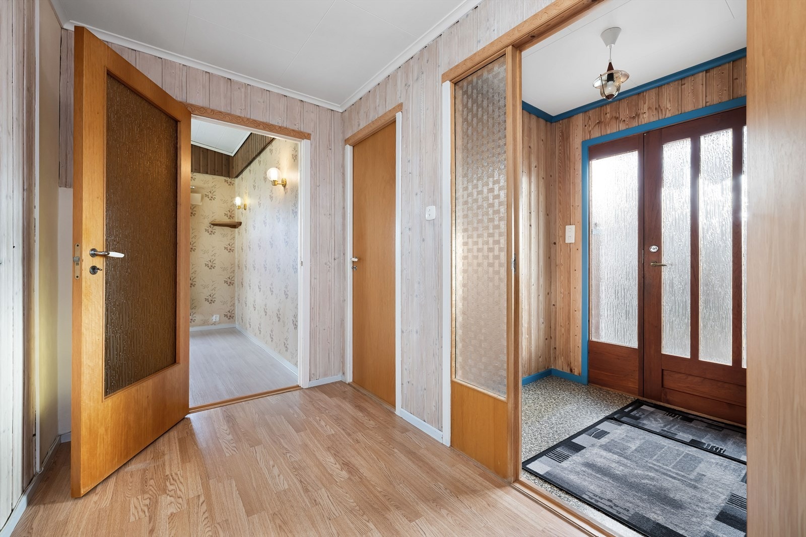 Hovedinngangen har belegg på gulvet og panel på veggene som skaper et lunt førsteinntrykk. Herfra kommer man inn i en lys gang med laminat på gulv, panel på vegger, og enkel tilgang til øvrige rom. Galleribilde