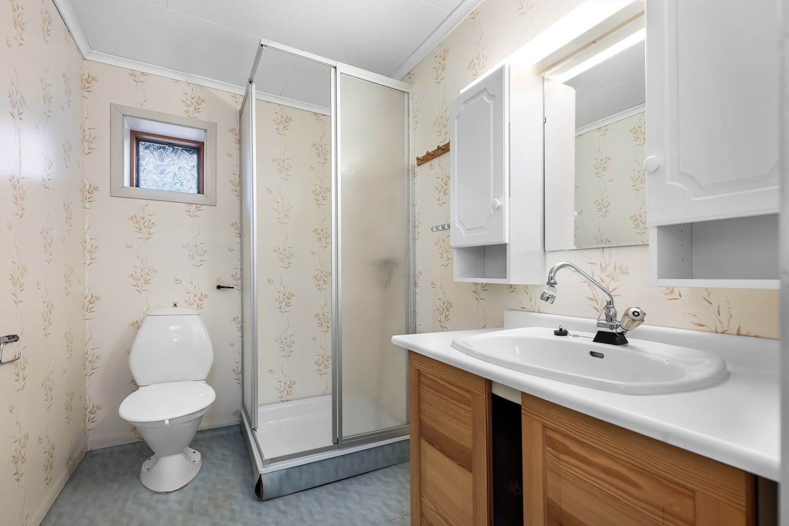 Badet i hybelen inneholder dusjkabinett og baderomsmøbel og har behov for oppgradering for å møte dagens krav til moderne komfort. Galleribilde