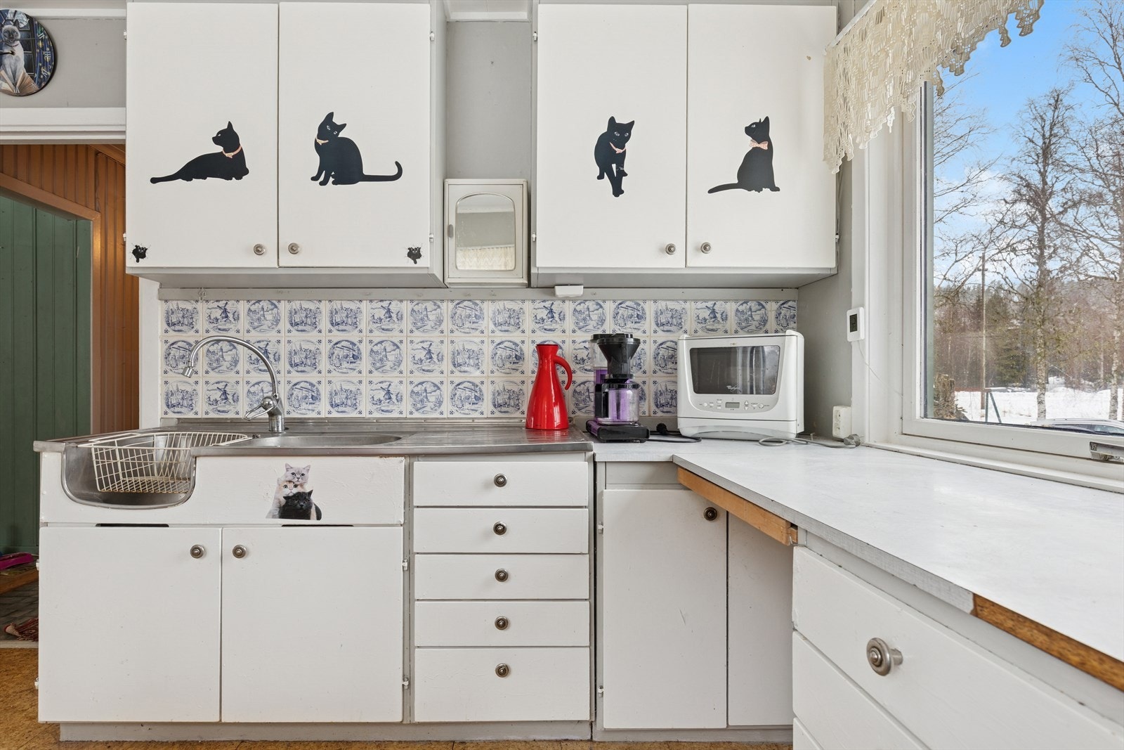 Eldre kjøkkeninnredning med glatte fronter, laminatbenkeplate og dobbel oppvaskkum i rustfritt stål. Galleribilde