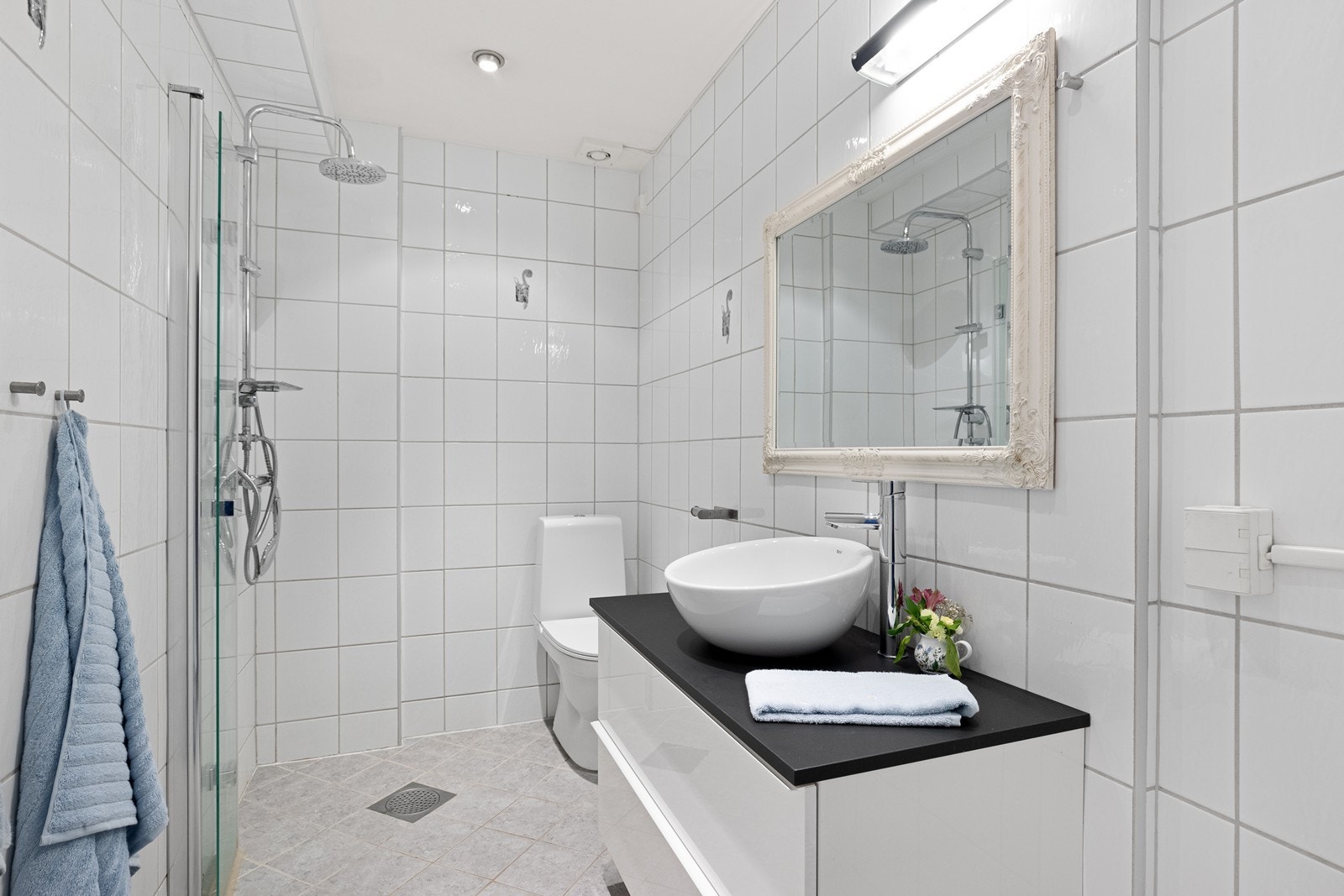 Flislagte vegger og gulv med elektriske varmekabler gir et funksjonelt bad fra 2004. Mekanisk avtrekk sikrer god ventilasjon, mens dusjvegg i glass gir en praktisk løsning. Galleribilde