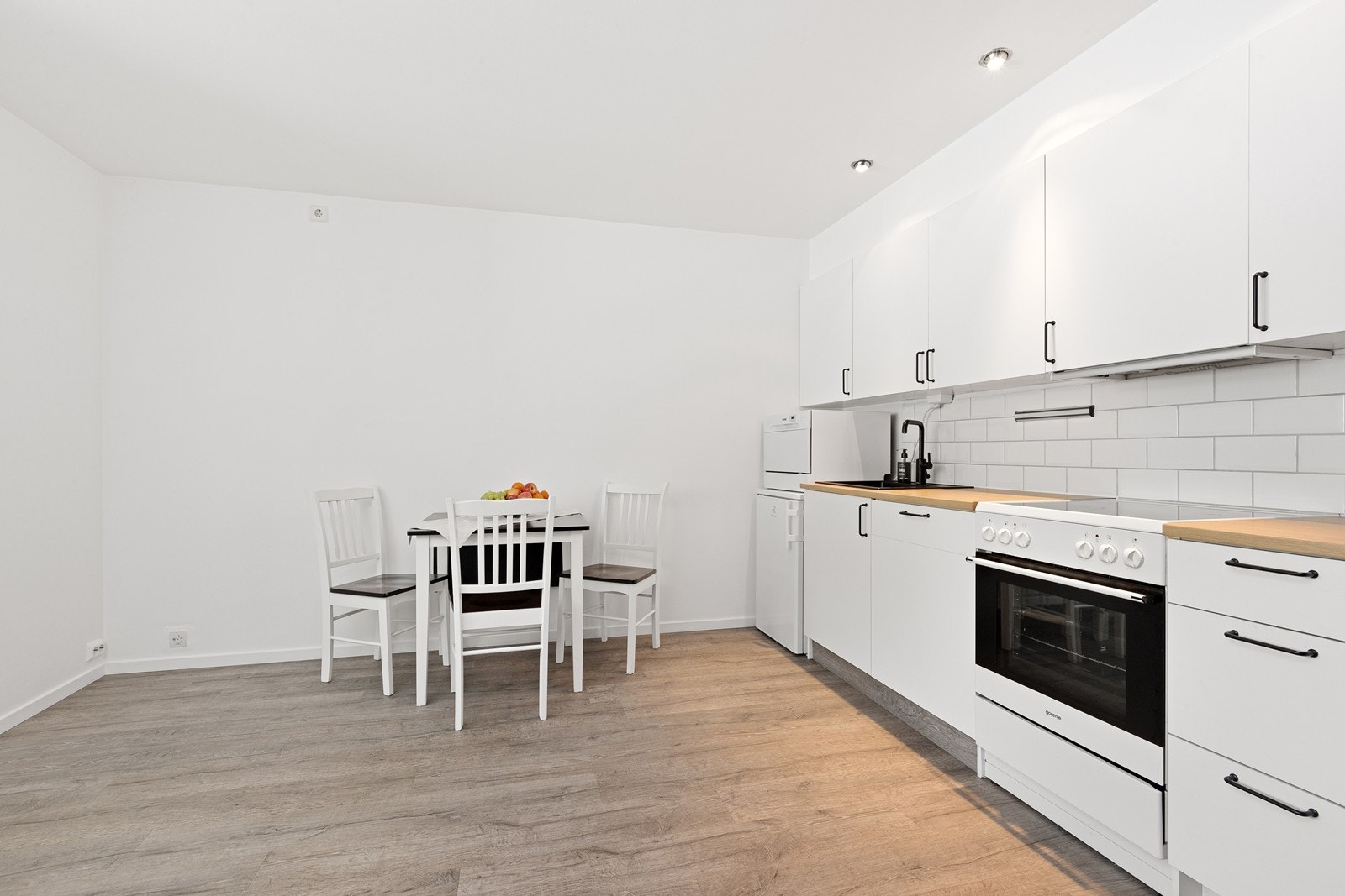 Hvite fronter og laminat benkeplate gir et ryddig og praktisk kjøkkenmiljø. Galleribilde