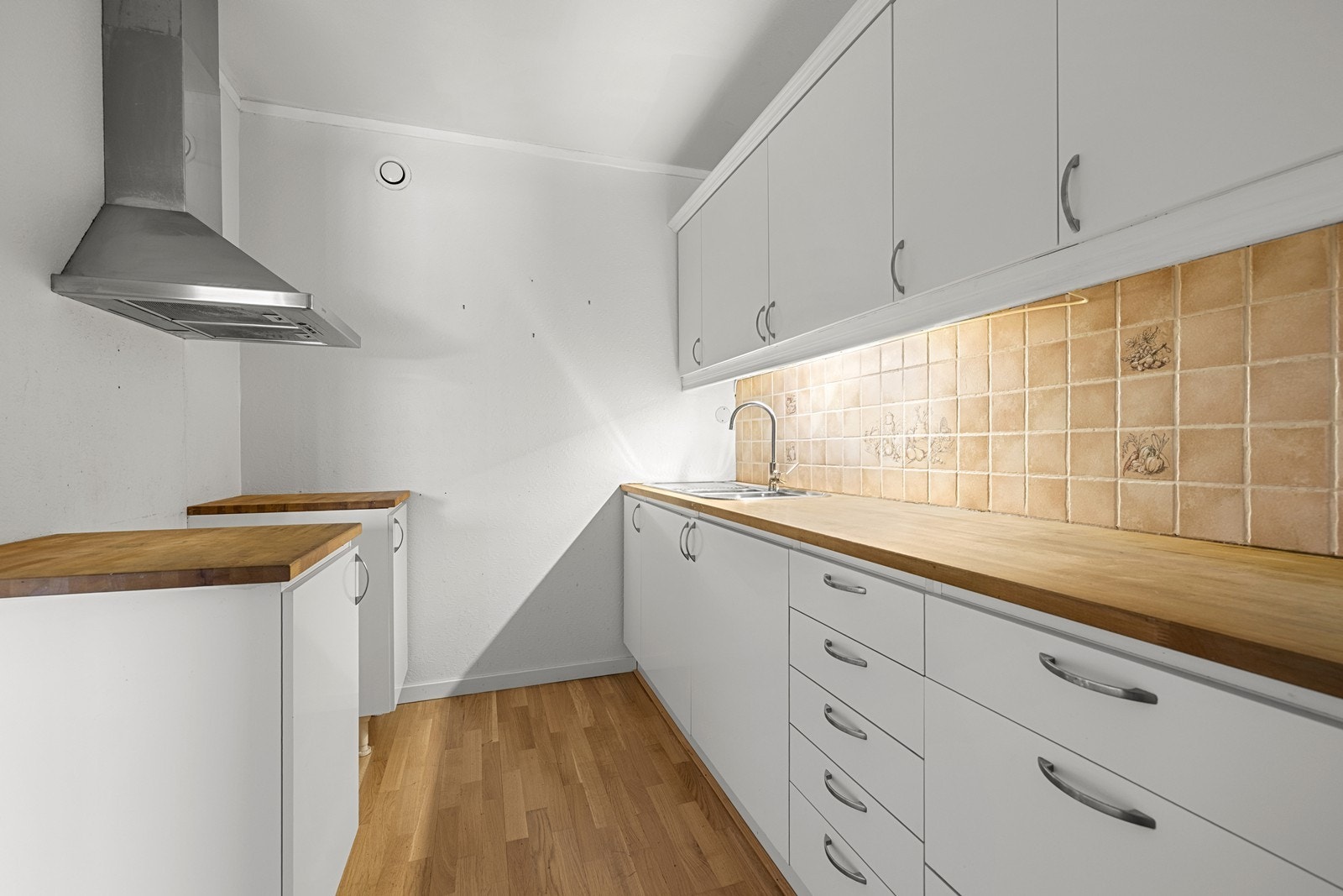 Kjøkkeninnredningen har slette fronter, benkeplate i tre og belysning under overskapene. Galleribilde