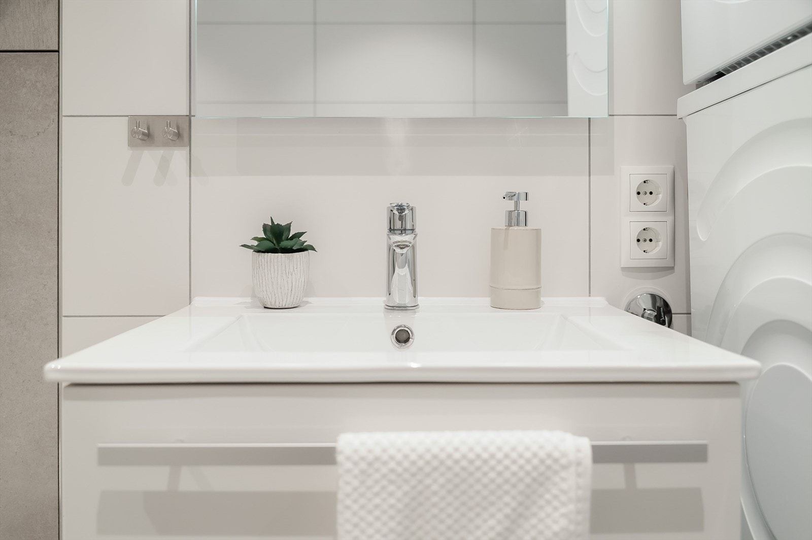 Stilren servantinnredning med gode oppbevaringsmuligheter samt speil med integrert belysning. Galleribilde