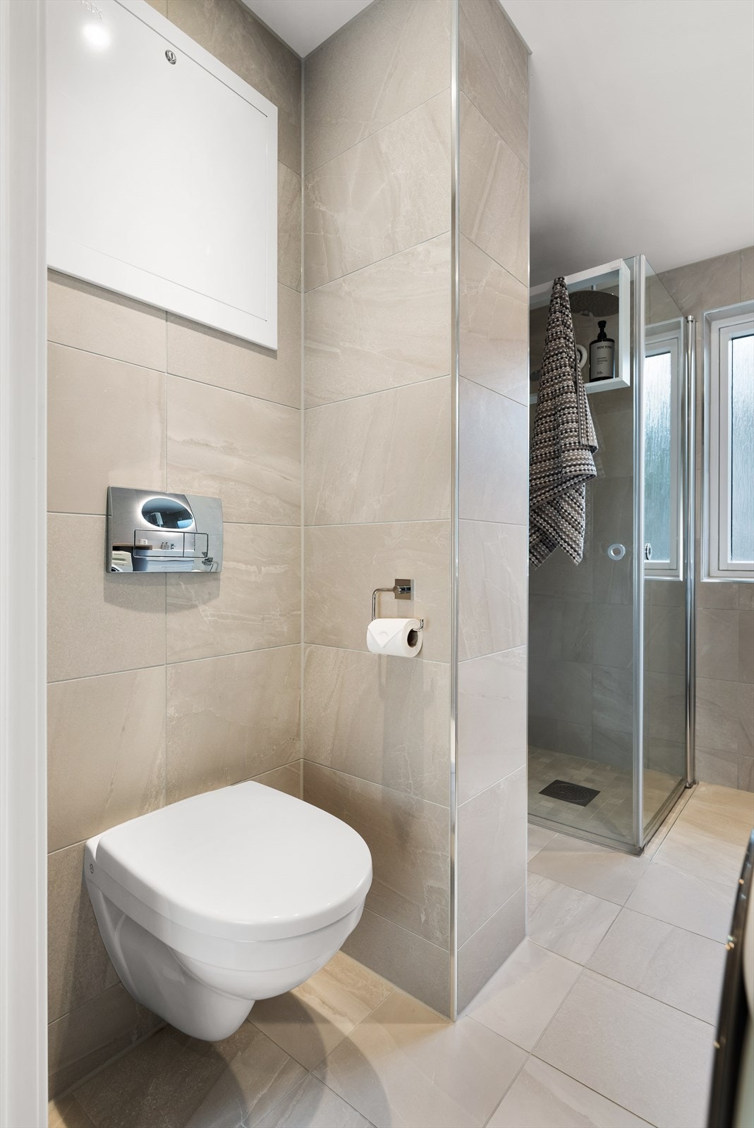 Badet er flislagt, har vegghengt toalett og foldbare dusjdører. Galleribilde