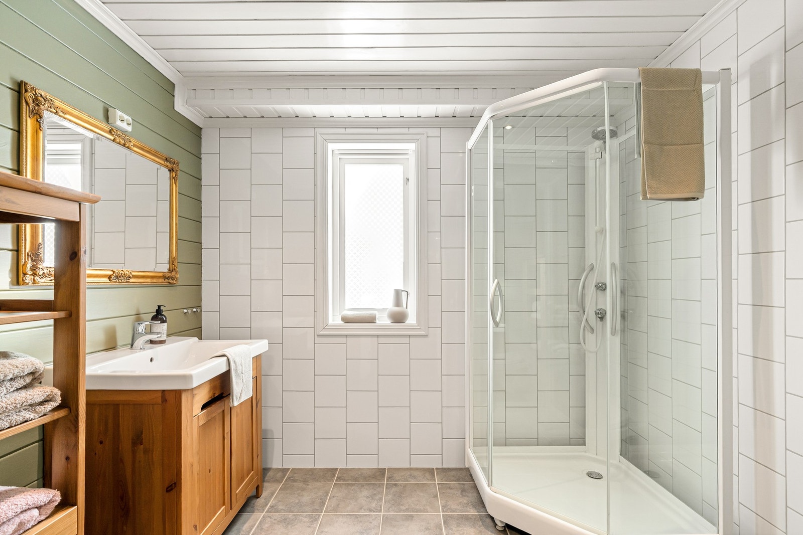 Badet er flislagt med dusjkabinett og servant Galleribilde