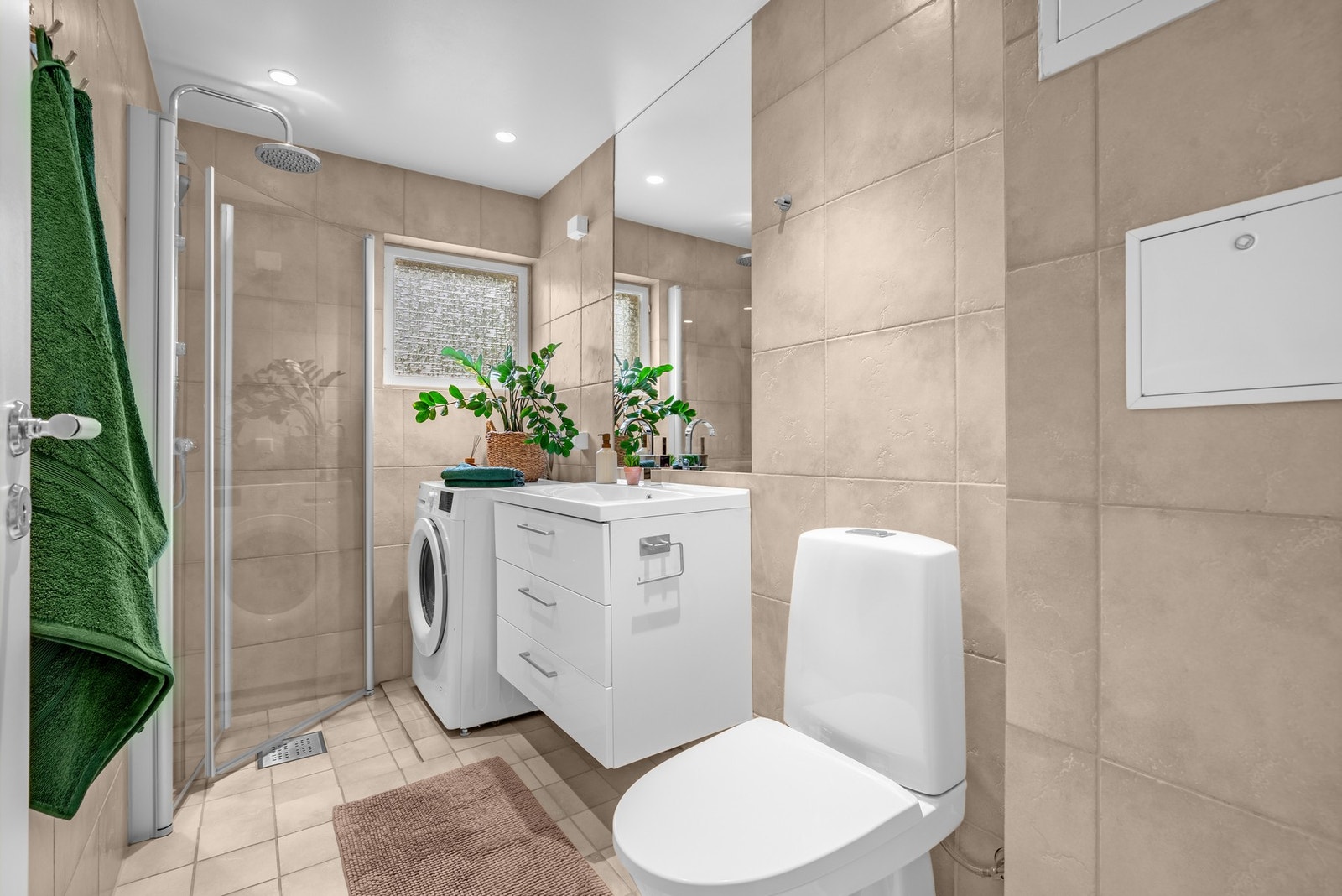 Flislagt bad, med varme i gulv og downlights i himling. Nedsenket dusjsone med svingdører i glass. Galleribilde