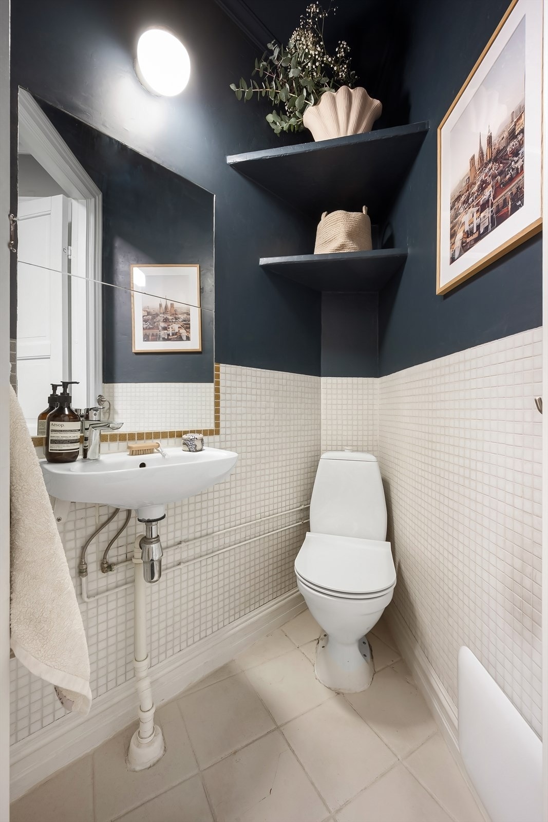 Separat toalettrom med flislagte overflater, innredet med gulvmontert toalett, servant og speil. Galleribilde