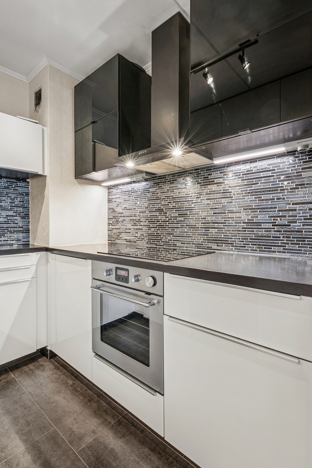 Innredning fra 2011 med glatte hvite fronter, hvor en del av overskapene har sorte glassdører med topphengsling. Galleribilde