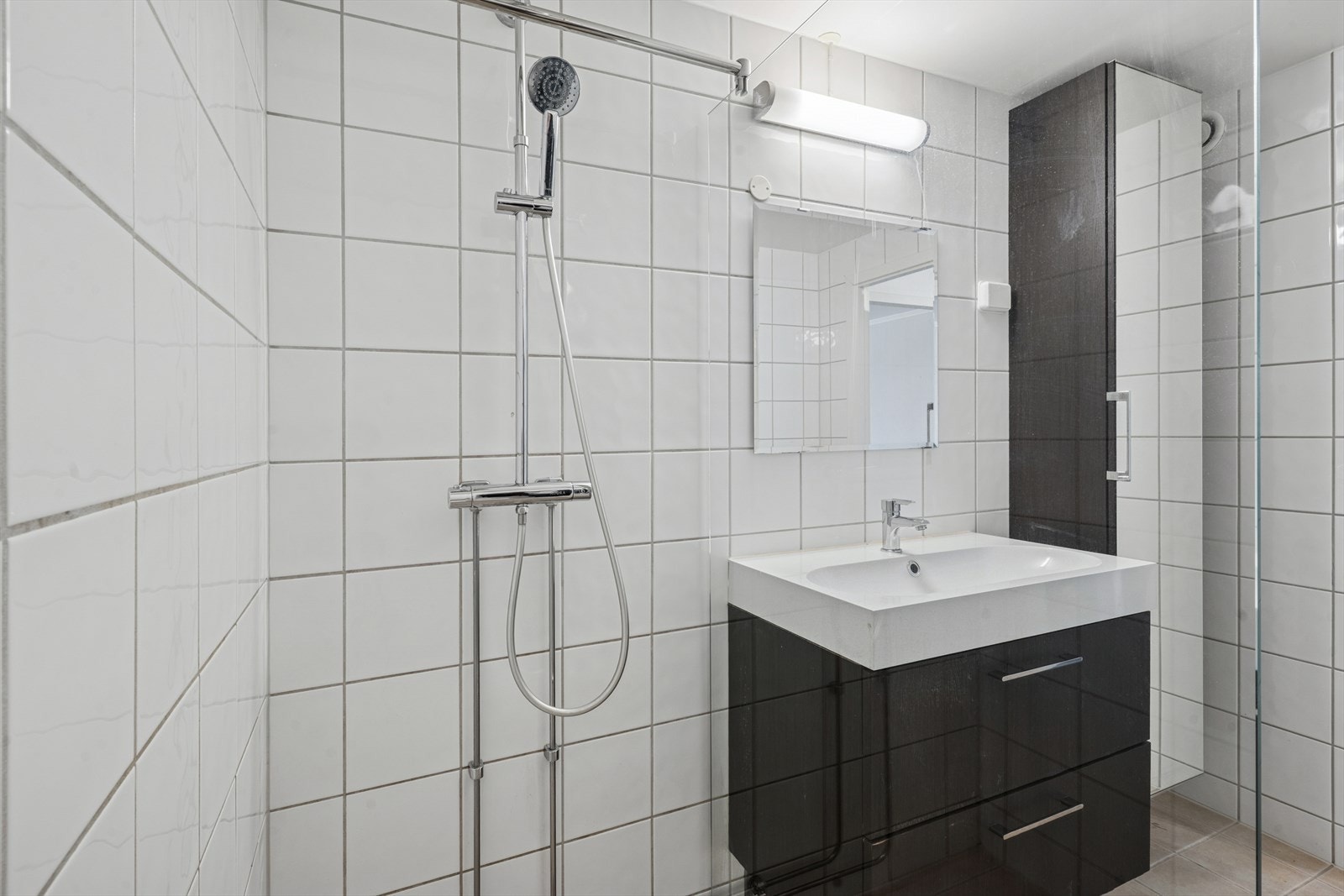 Badet er utstyrt med dusj med glassvegg, baderomsinnredning med servant, samt veggskap. Galleribilde