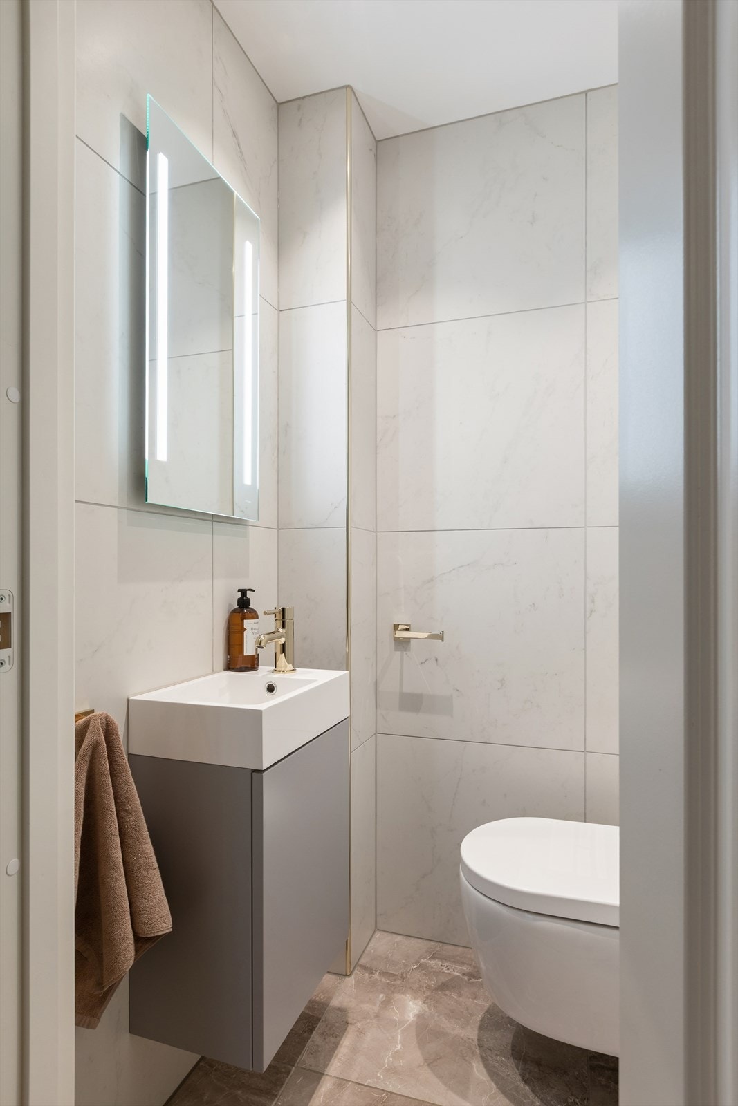 Flislagt toalettrom fra 2022 i samme stil som hovedbadet. Vegghengt toalett og skjult sisterne. Galleribilde