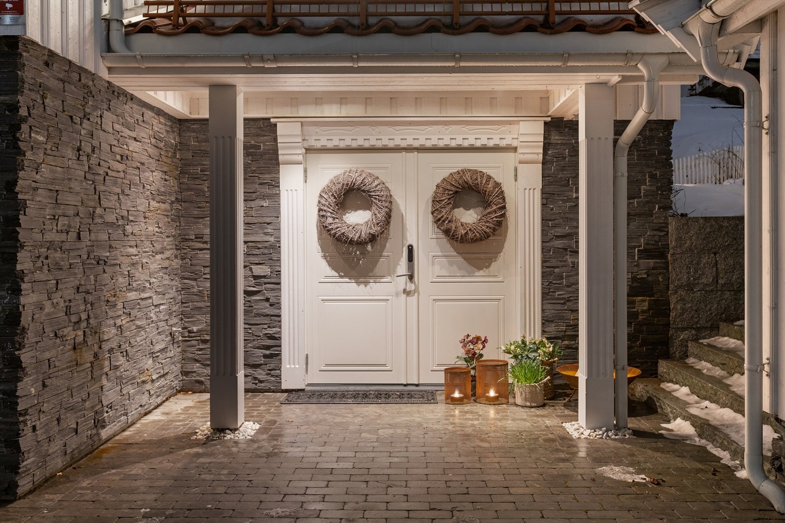 Overbygget inngangsparti med dekorativ fasade i skifer og en tofløyet profilert ytterdør med elektronisk dørlås. Galleribilde