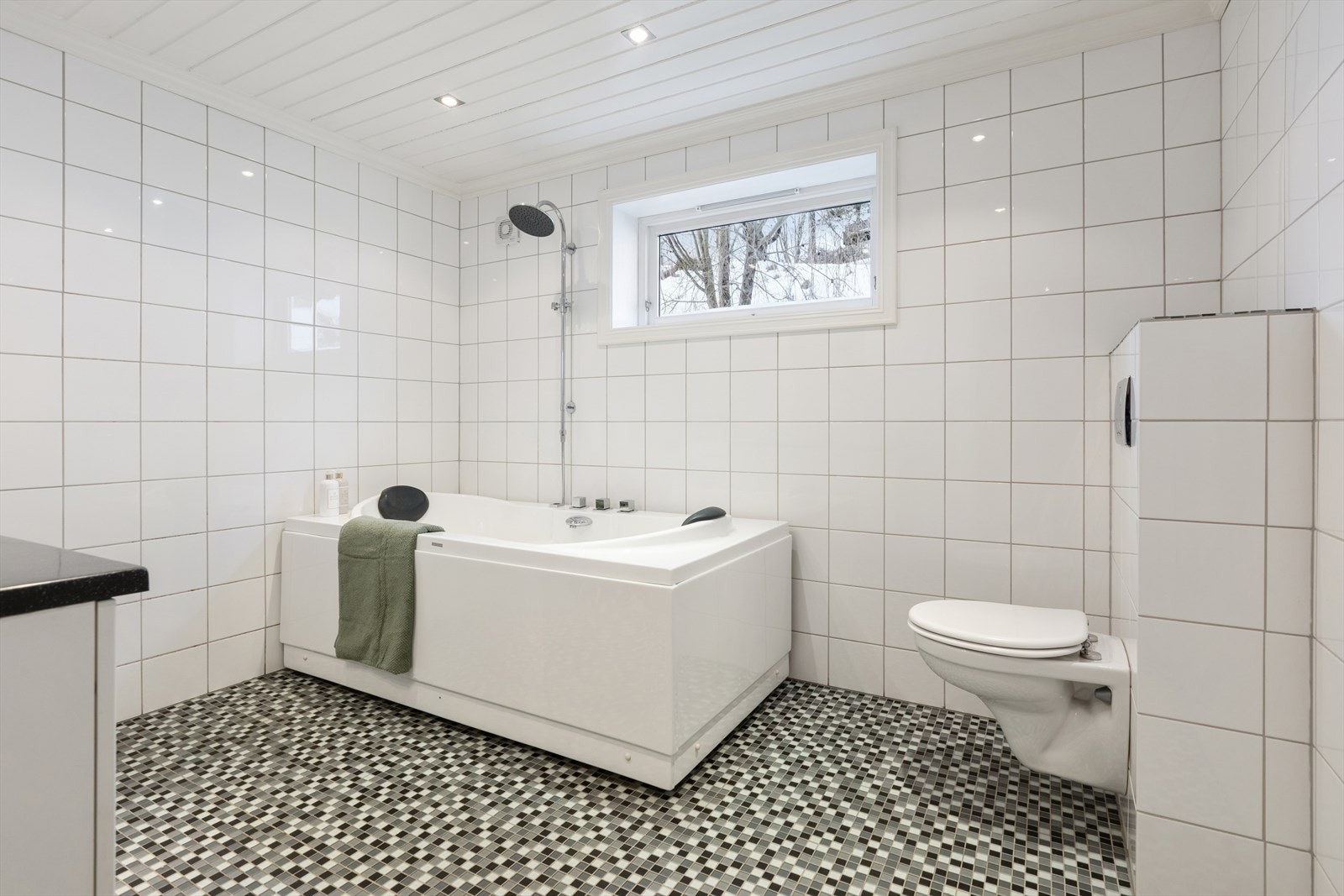 På badet er det vegghengt toalett, badekar med dusjgarnityr, og baderomsinnredning med servant, underskap, speil og lys. Opplegg for vaskemaskin. Galleribilde