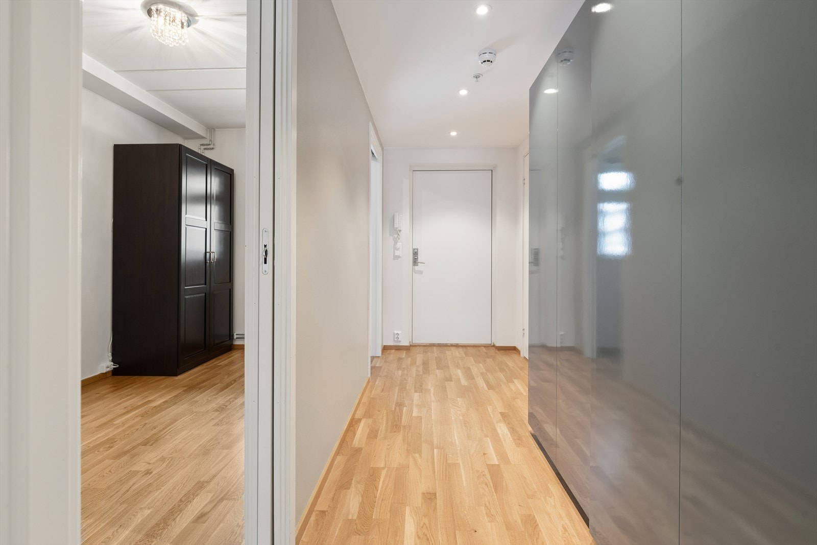 Velkommen inn i en lys entré. Porttelefon og downlights i tak. Det er to skyvedører inn til hovedsoverommet. Galleribilde