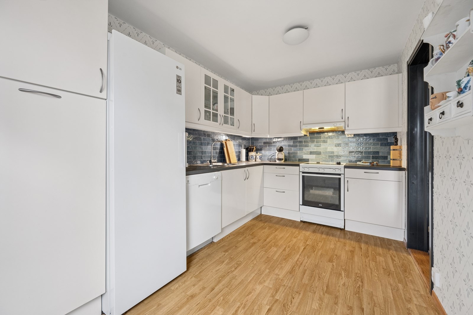 Kjøkkenet ligger separat fra stuen og er tidløst innredet med hvite, slette fronter og mørk benkeplate i laminat. Her har man godt med skap- og skuffeplass, samt gode arbeidsflater på benk. Galleribilde