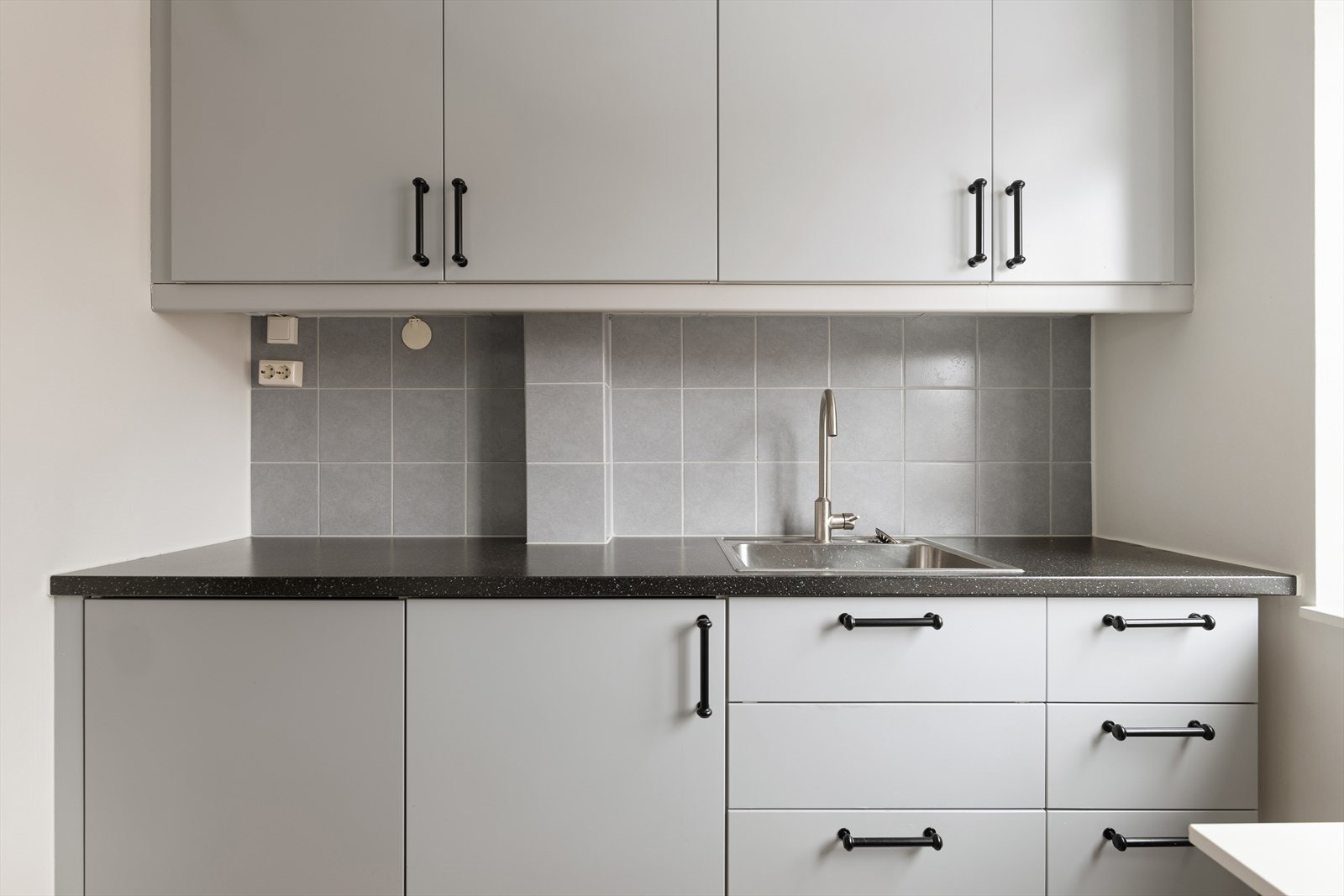 Mellom over- og underskapene er det en praktisk backsplash som gjør rengjøringen enkel, og innredningen har integrert belysning som gir både funksjon og stemning. Galleribilde