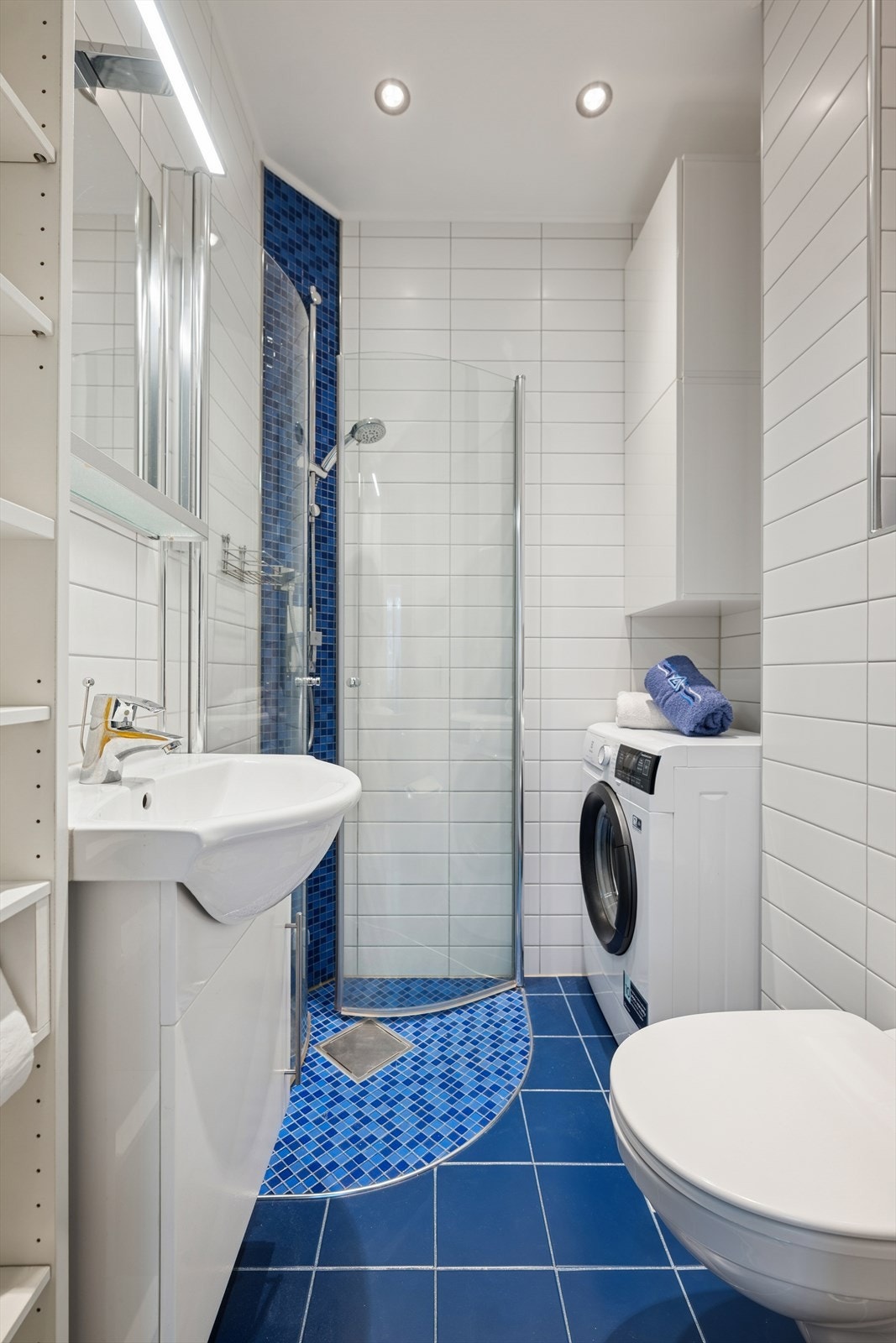 Badet fra 2015 fremstår moderne og funksjonelt, med fliser på både gulv og vegger som gir et rent og helhetlig uttrykk. Her finner du også opplegg for vaskemaskin, praktiske oppbevaringsmuligheter og varmekabler i gulv. Galleribilde