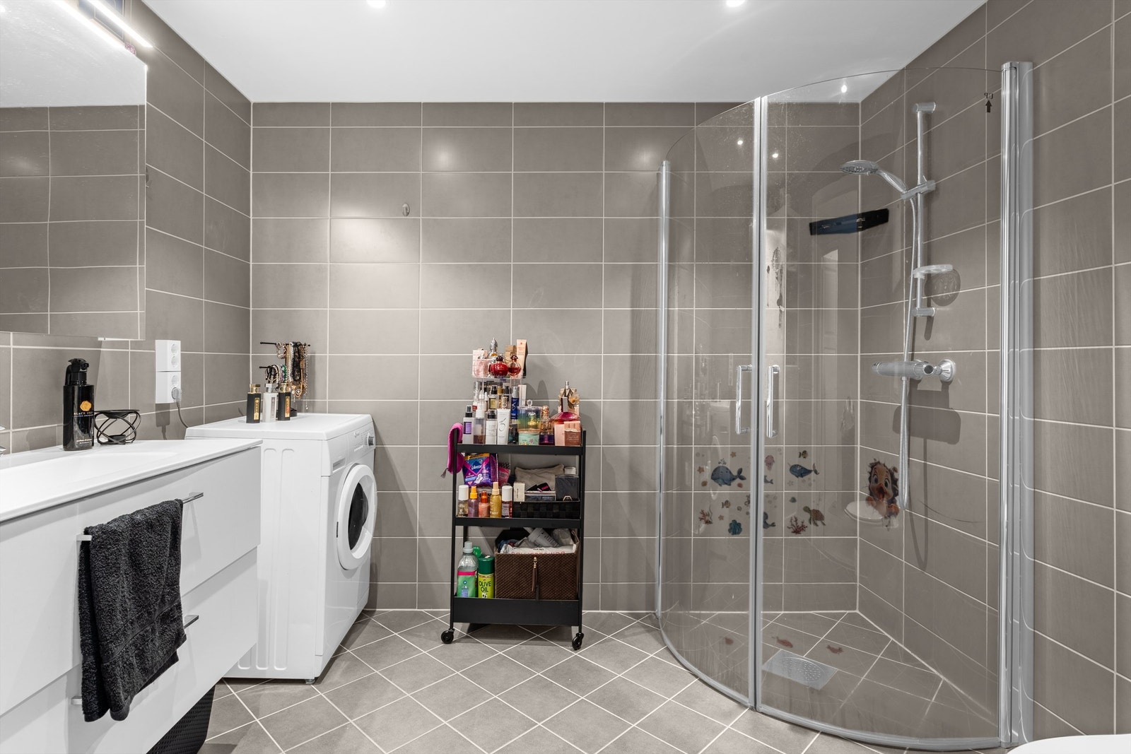 Badet har buede dusjdører i glass. Det er opplegg for vaskemaskin og ev. tørketrommel Galleribilde