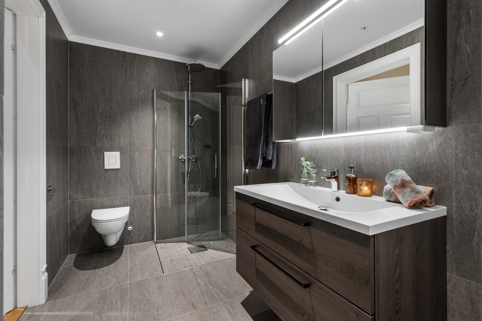 Badet fremstår meget delikat med store grå fliser på både vegger og gulv, som gir et moderne og stilrent uttrykk. Galleribilde
