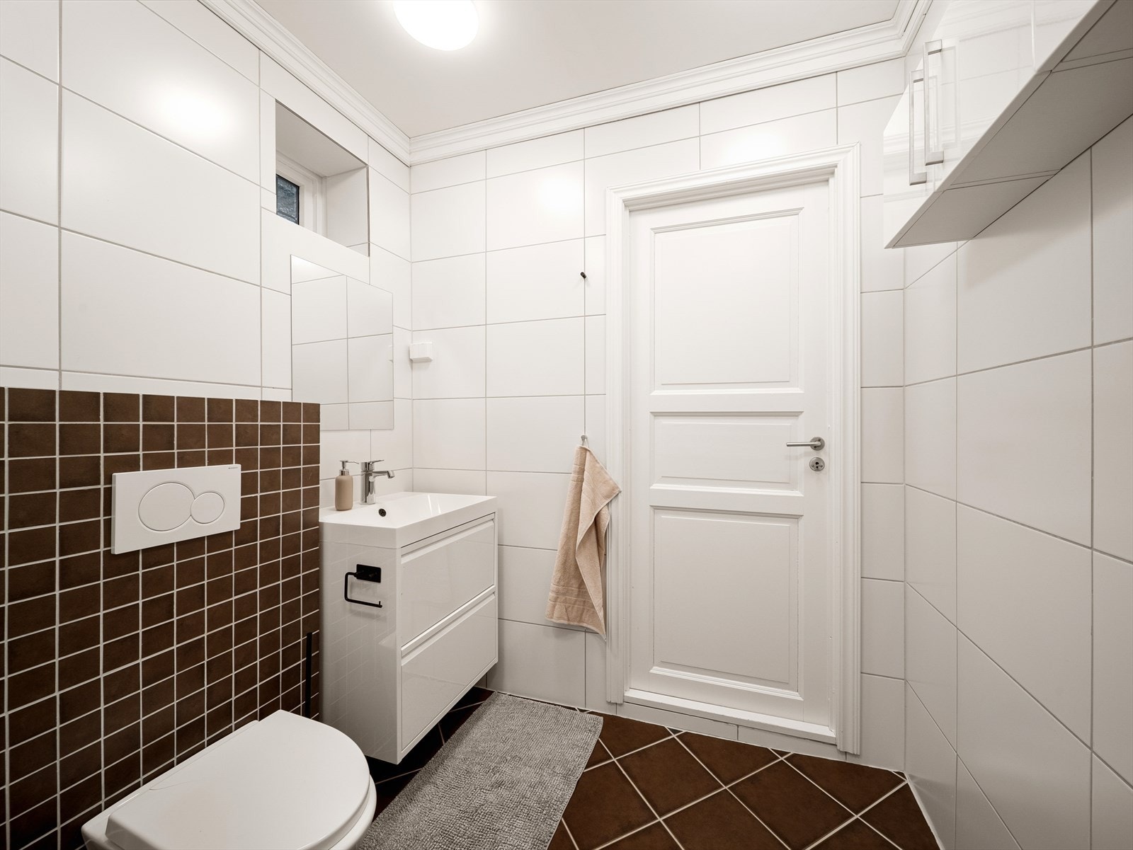 Badet er innredet med servant i baderomsmøbel, veggmontert toalett og dusjkabinett. Galleribilde