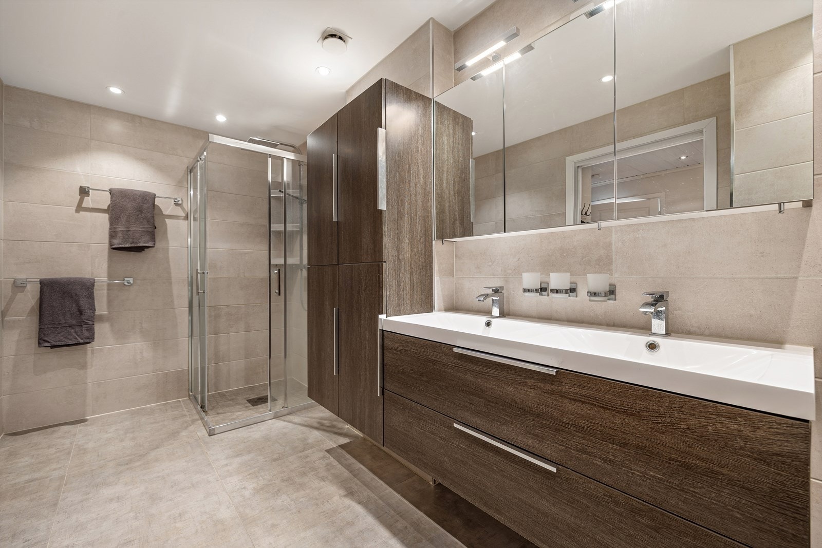 Badet er utstyrt med dusjhjørne, opplegg for vaskemaskin og stor servantinnredning med rikelig lagringsplass. Galleribilde