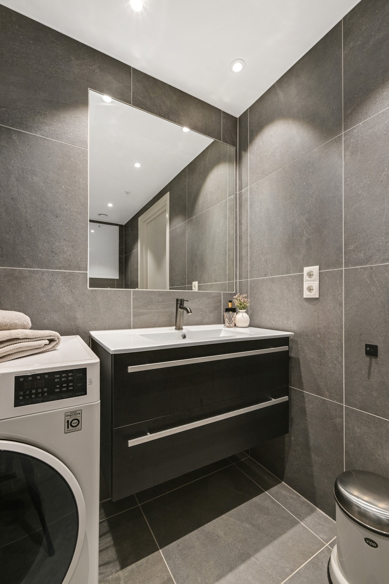 Det er vegghengt toalett, pen baderomsinnredning og speil Galleribilde