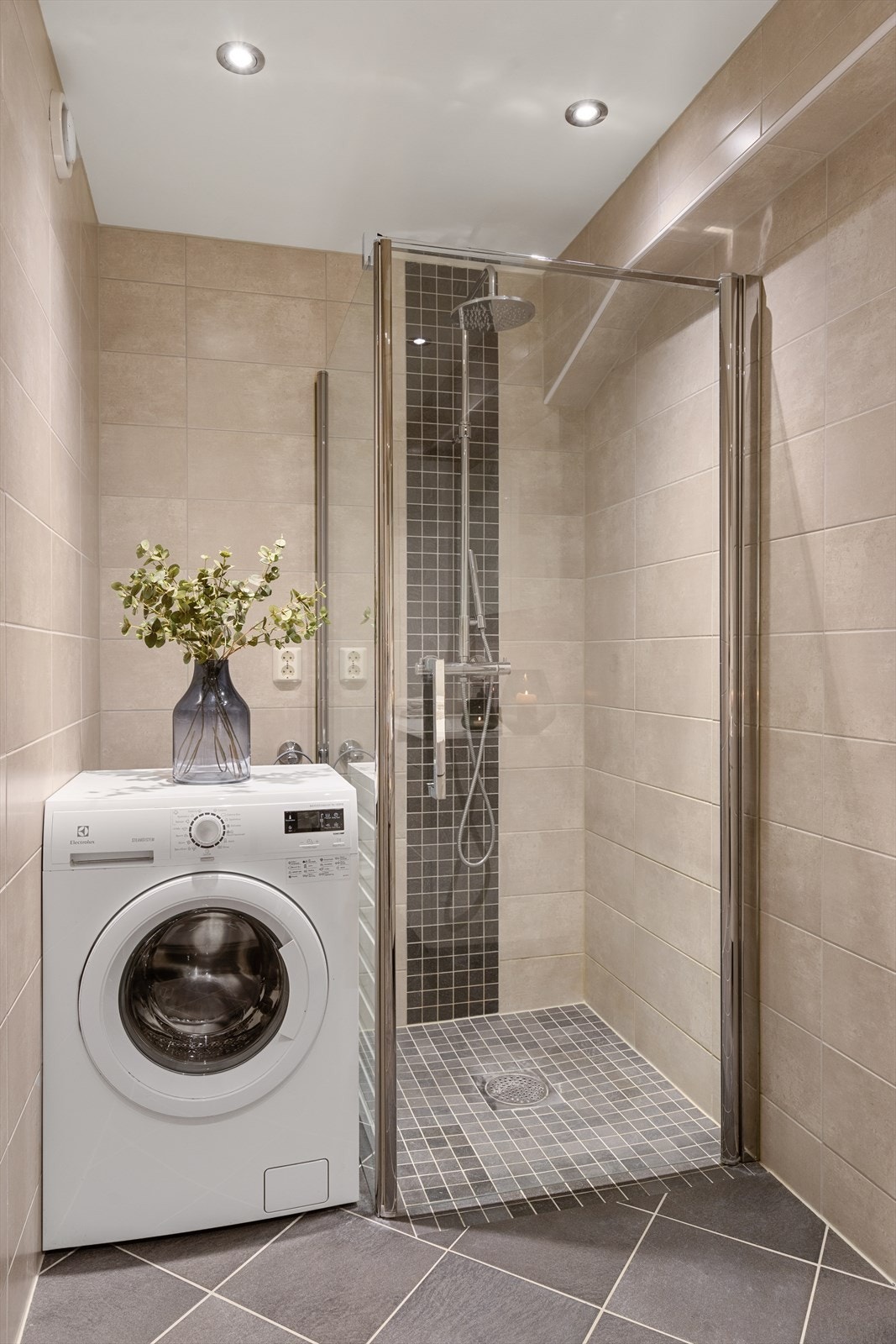 Badet har vegghengt toalett med innbygget sisterne, dusjhjørne med foldedører og opplegg for vaskemaskin. Galleribilde