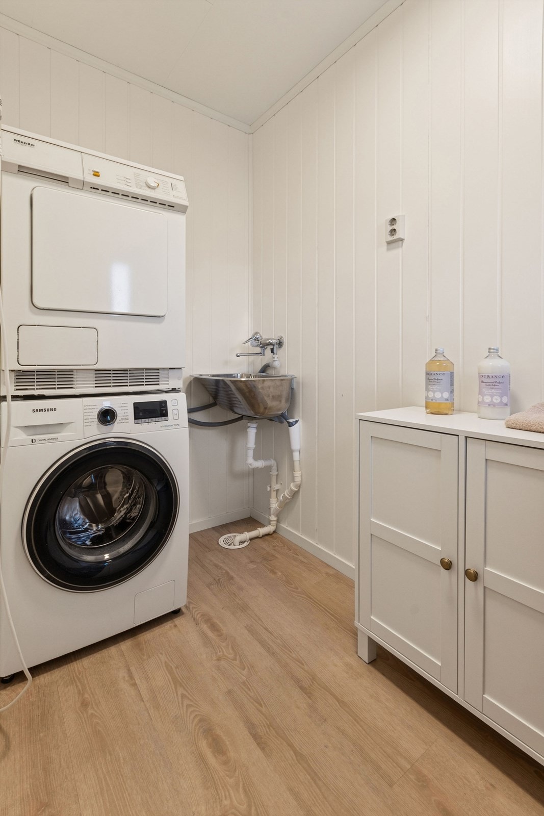 Eget, praktisk vaskerom med servant og opplegg for vaskemaskin. Galleribilde