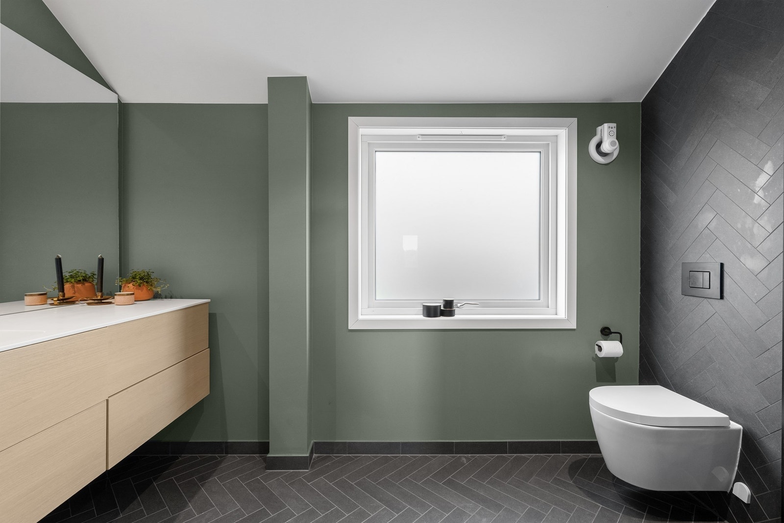 Vegghengt toalett, stor servant med skuffer til oppbevaring og stor speil på vegg Varmekabler i gulv.
Stort vindu, som er av nyere alder. Galleribilde