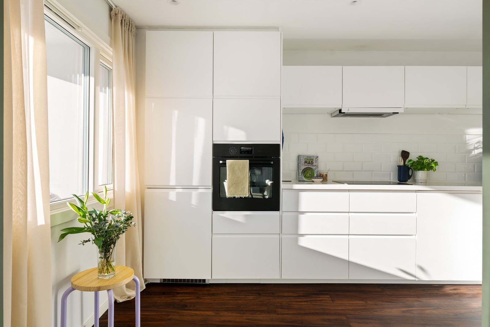 Kjøkkeninnredningen har slette fronter, fliser over benkeplaten og integrerte hvitevarer. Galleribilde