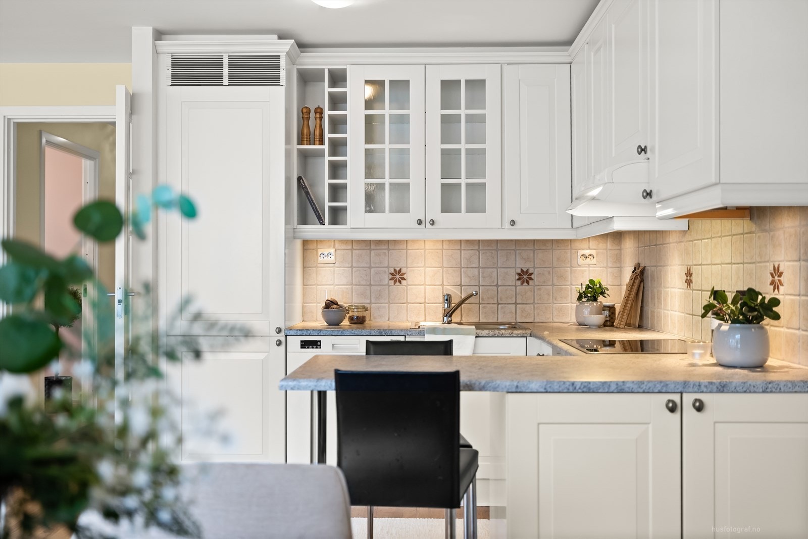 Pen kjøkkeninnredning med profilerte fronter og benkeplate av laminat. Vegg over benkeplaten er flissatt. Galleribilde