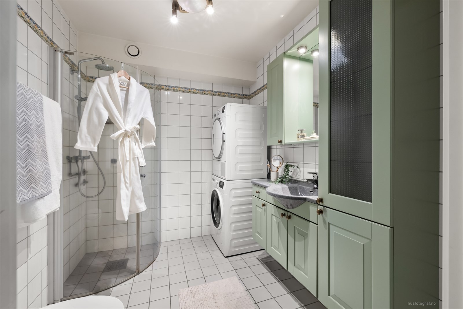 Badet har en med romslig servantinnredning malt i en dus grønntone, dusjhjørne med innfellbare dusj dører og toalett. Rommet har opplegg til vaskemaskin og tørketrommel. Galleribilde