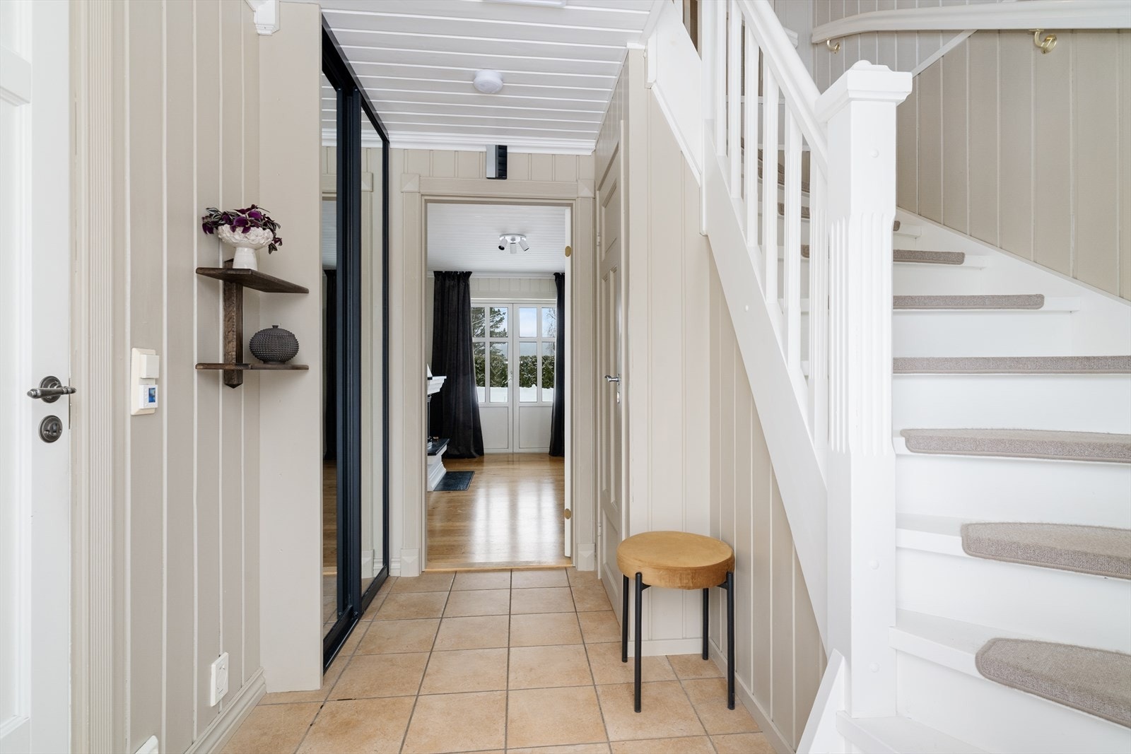 Fin og romslig entre med flislagt gulv og varmekabler, samt praktisk skyvedørsgarderobe for skjult oppbevaring av sko- og yttertøy. Galleribilde