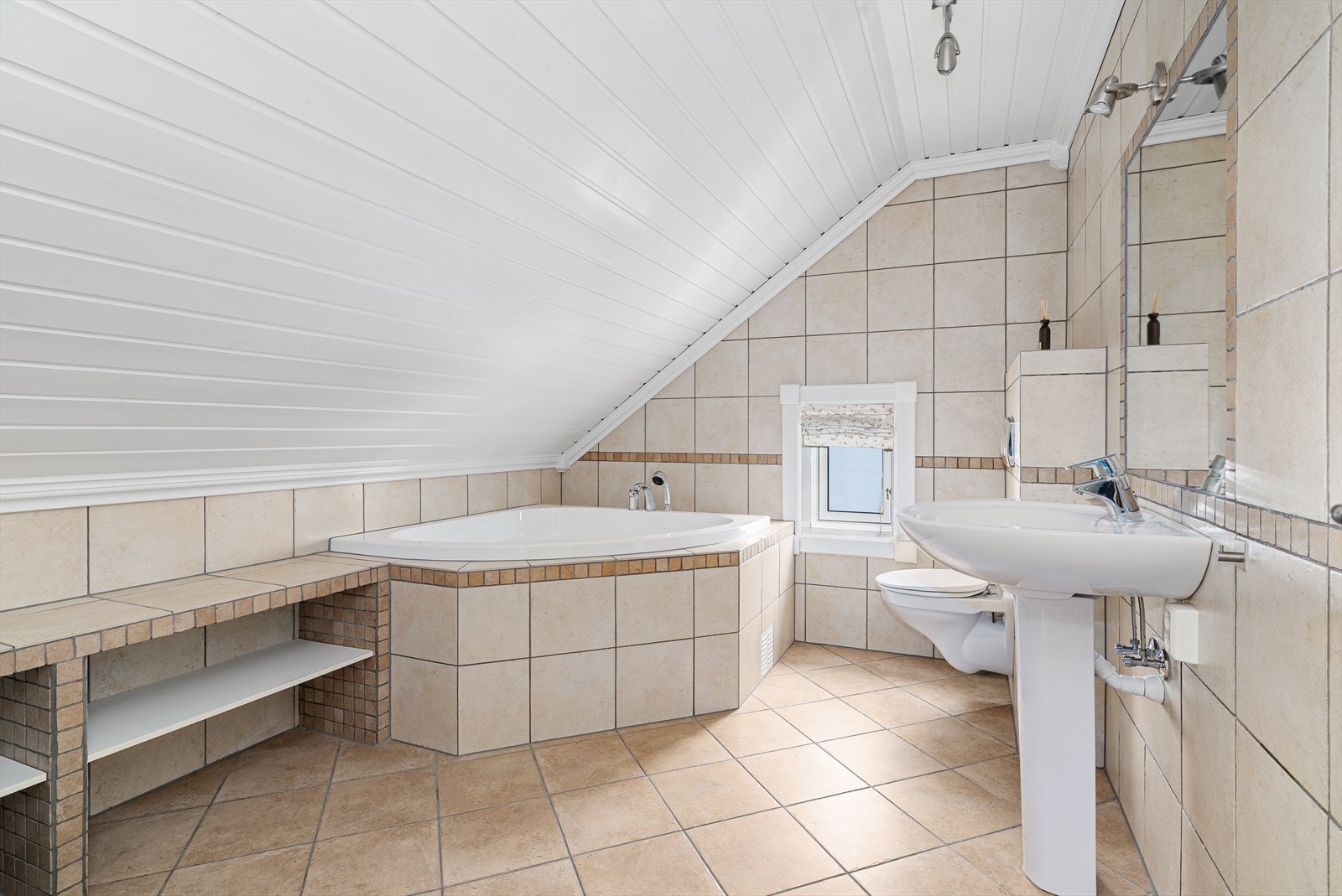 Pent, flislagt bad i 2. etasje. Badet har elektriske varmekabler i gulv, veggmontert toalett og servant, samt innfliset badekar i hjørnet. Galleribilde