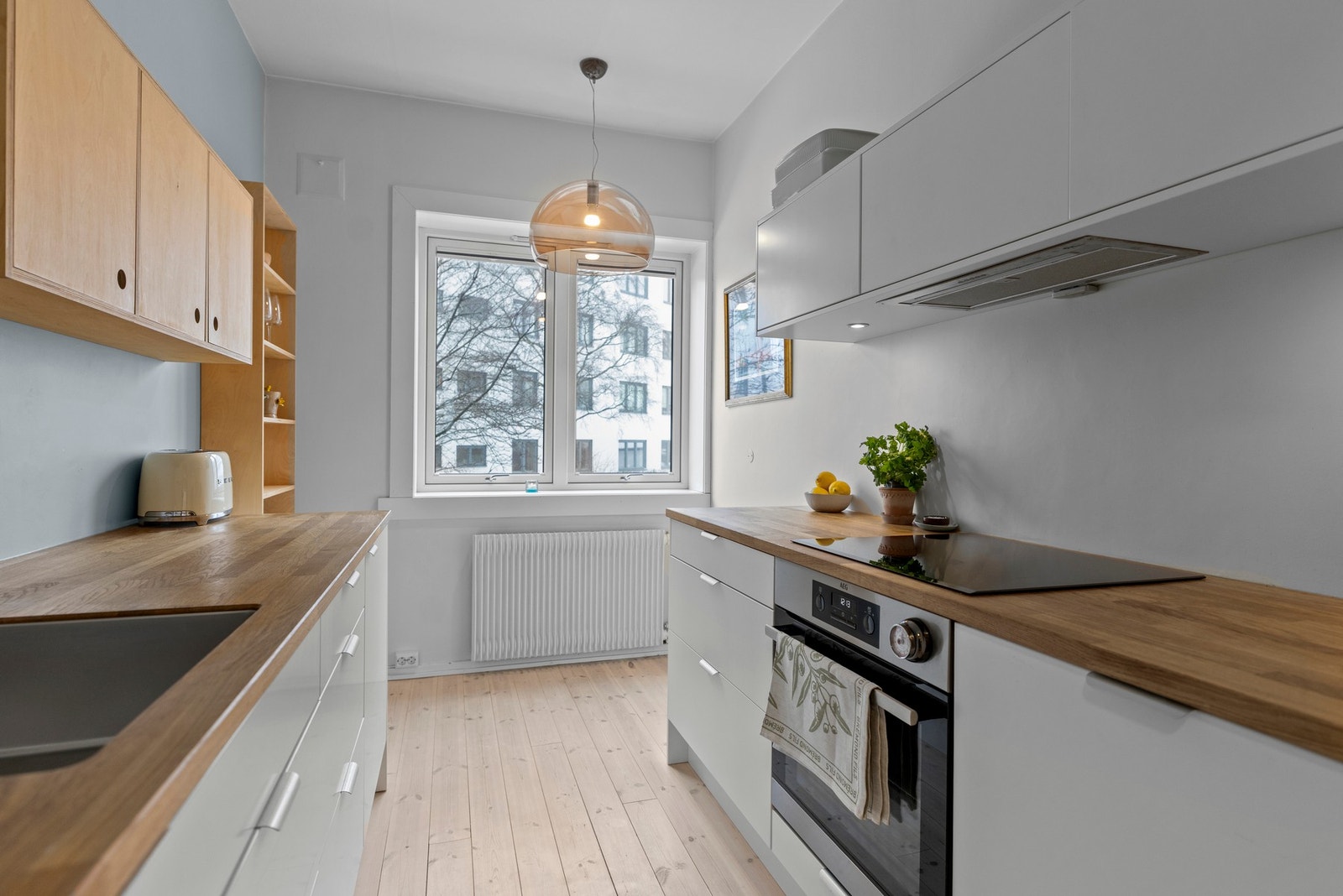 Kjøkkenet har en funksjonell innredning med glatte fronter og en benkeplate i heltre som gir god arbeidsflate Galleribilde