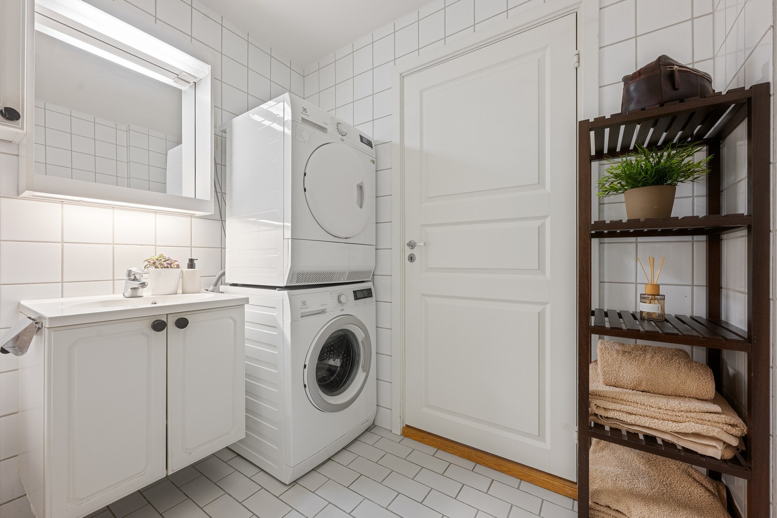 Bad med flislagt gulv og vegger, badekar og opplegg for vaskemaskin. Galleribilde