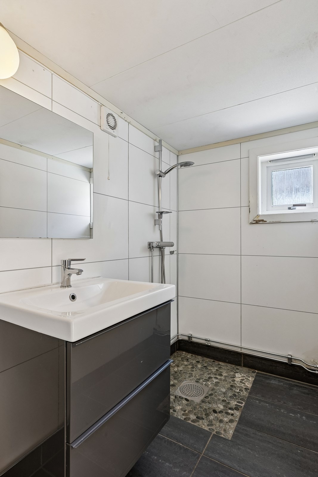 Rommet er innredet med servantskap, frittstående toalett og en dusjnisje. Galleribilde