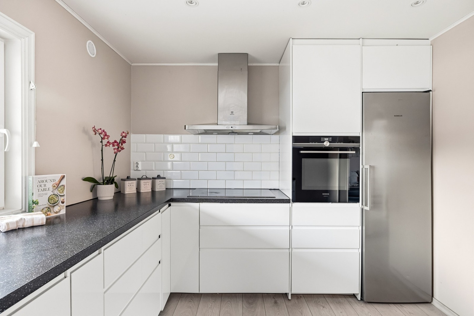 Videre er det stedvis flislagt over benkeplate og 3 doble stikkontakter på vegg, innebygget stekeovn i høyskap, innebygget oppvaskmaskin og frittstående kjøleskap er plassert i nisje. Galleribilde