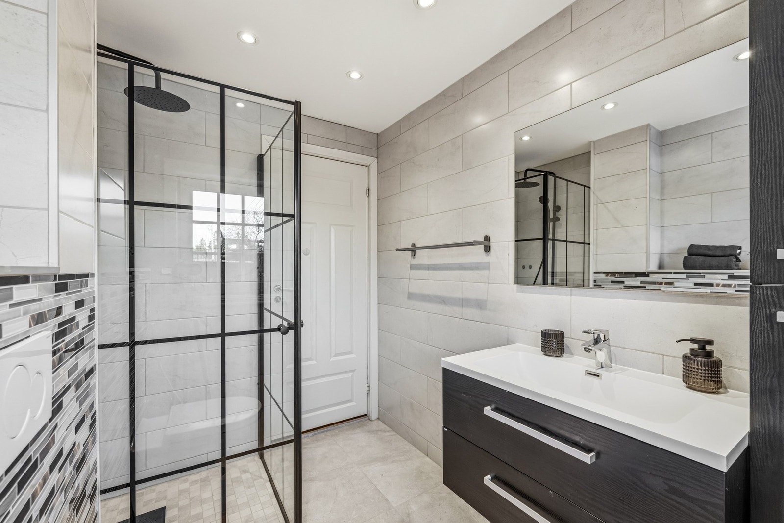 Baderommet i boligens 1. etasje har overflater fra 2018. Høyskap og innredning med servant med ett-greps armatur, speil samt dobbel stikkontakt på vegg. Galleribilde