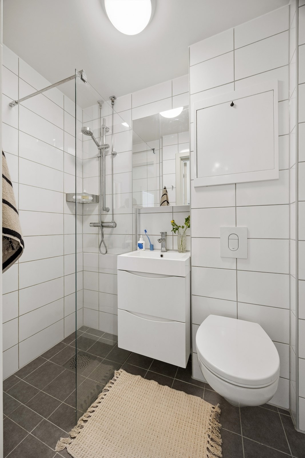 Innredningen består av et stilrent servantskap i hvit glatt utførelse med heldekkende servant, overskap med speildører, vegghengt toalett og et praktisk dusjhjørne med glassvegg. Opplegg for vaskemaskin er plassert på kjøkkenet. Galleribilde