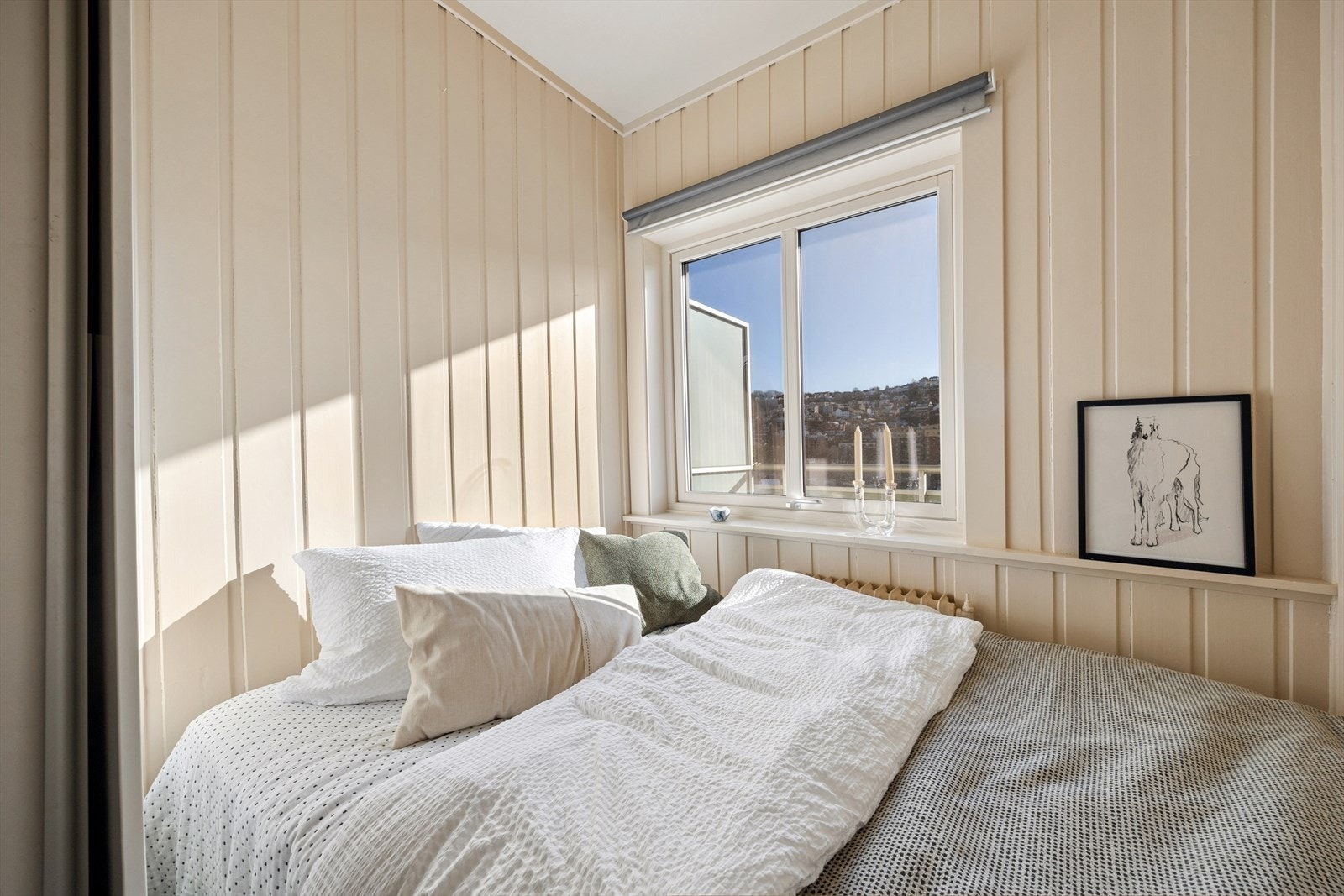 Rommet har malte vegger i trepanel og et vindu som slipper inn dagslys. Galleribilde